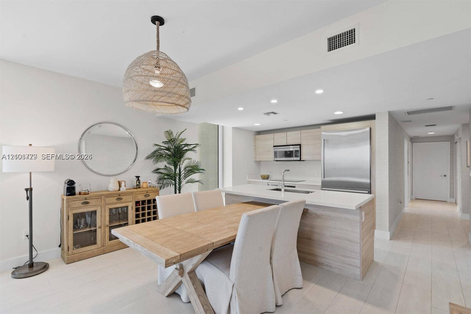 Open-concept kitchen featuring light wood-finish cabinetry, quartz countertops, stainless steel appliances, recessed lighting, and large-format flooring