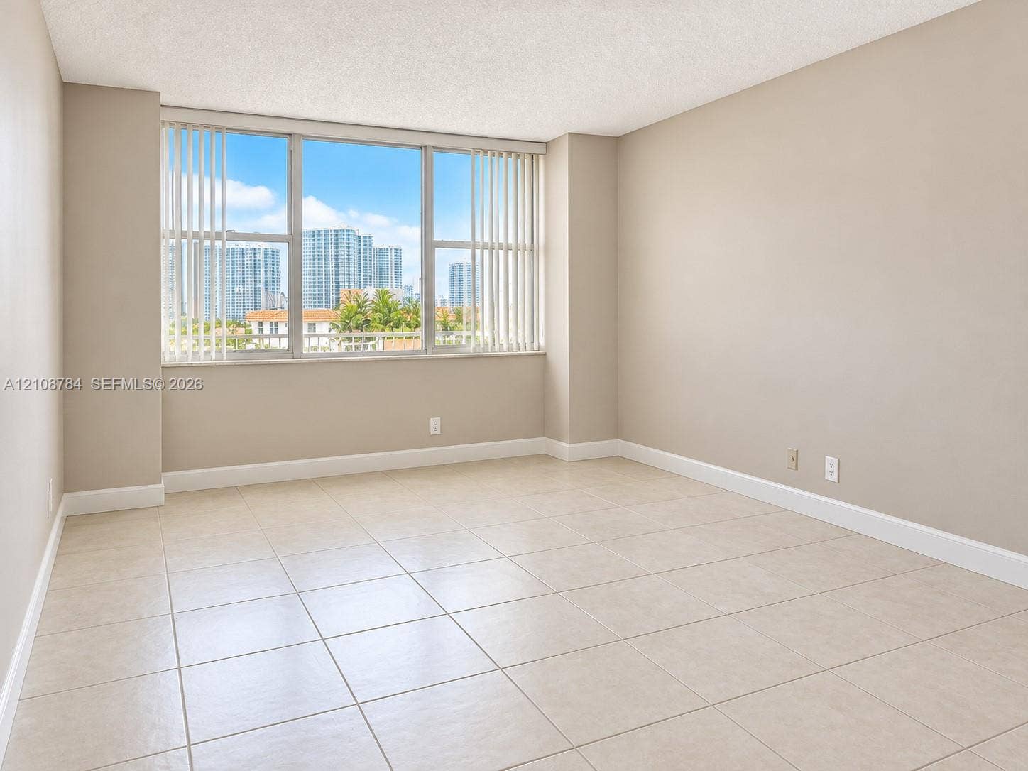 Spacious room featuring neutral tile flooring, expansive windows, and vertical blinds