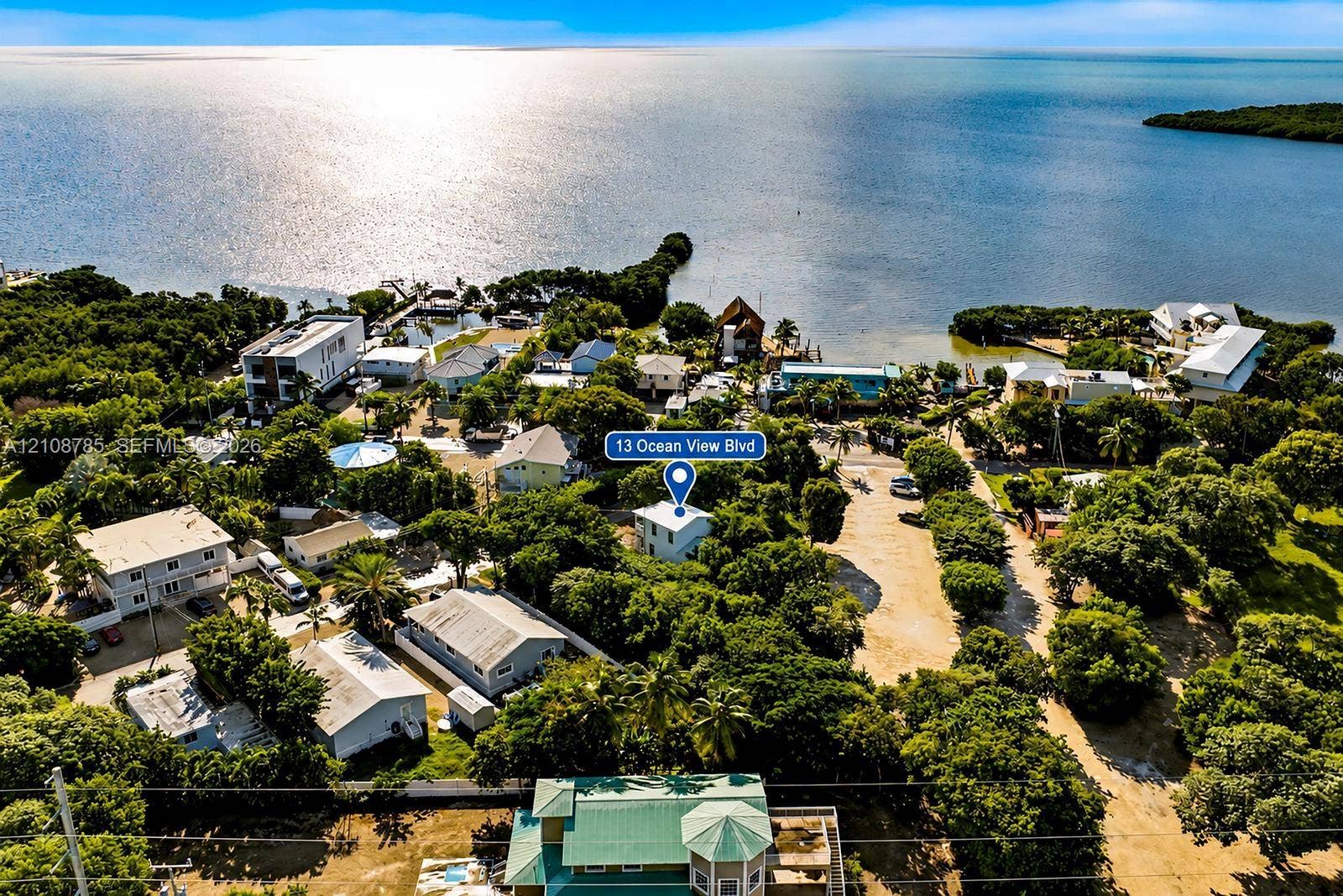 Aerial perspective of a coastal residential property surrounded by mature tree canopy and proximity to open water