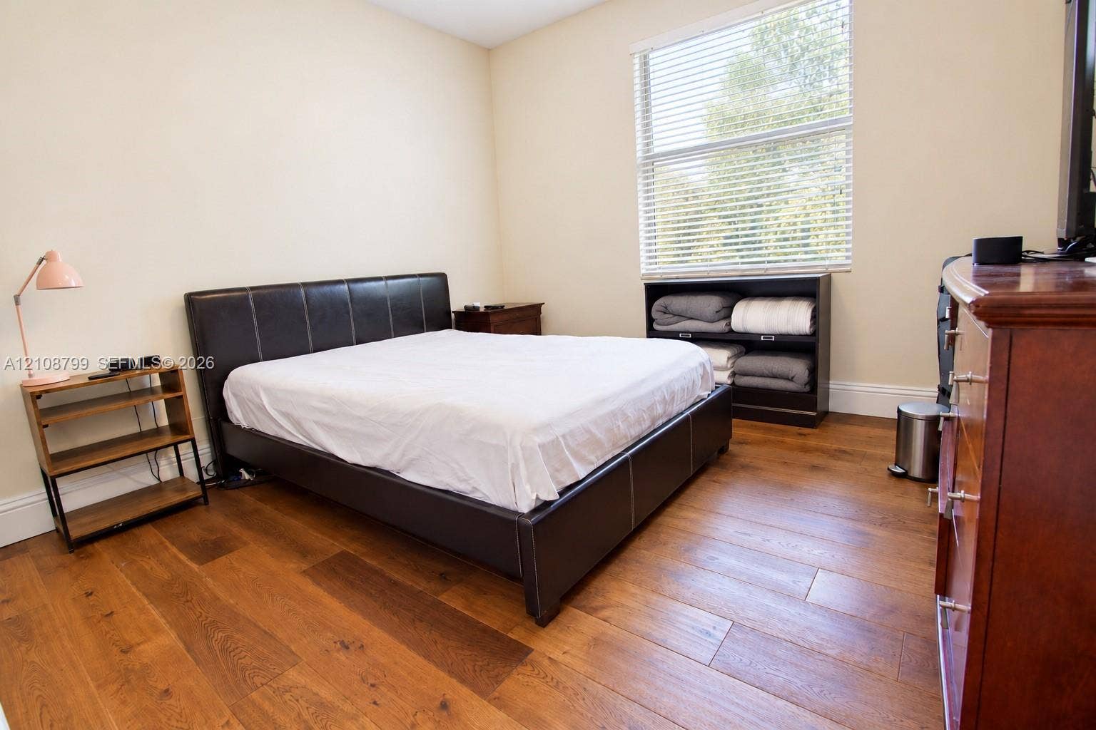 Wood-finish flooring, neutral wall tones, and horizontal window blinds