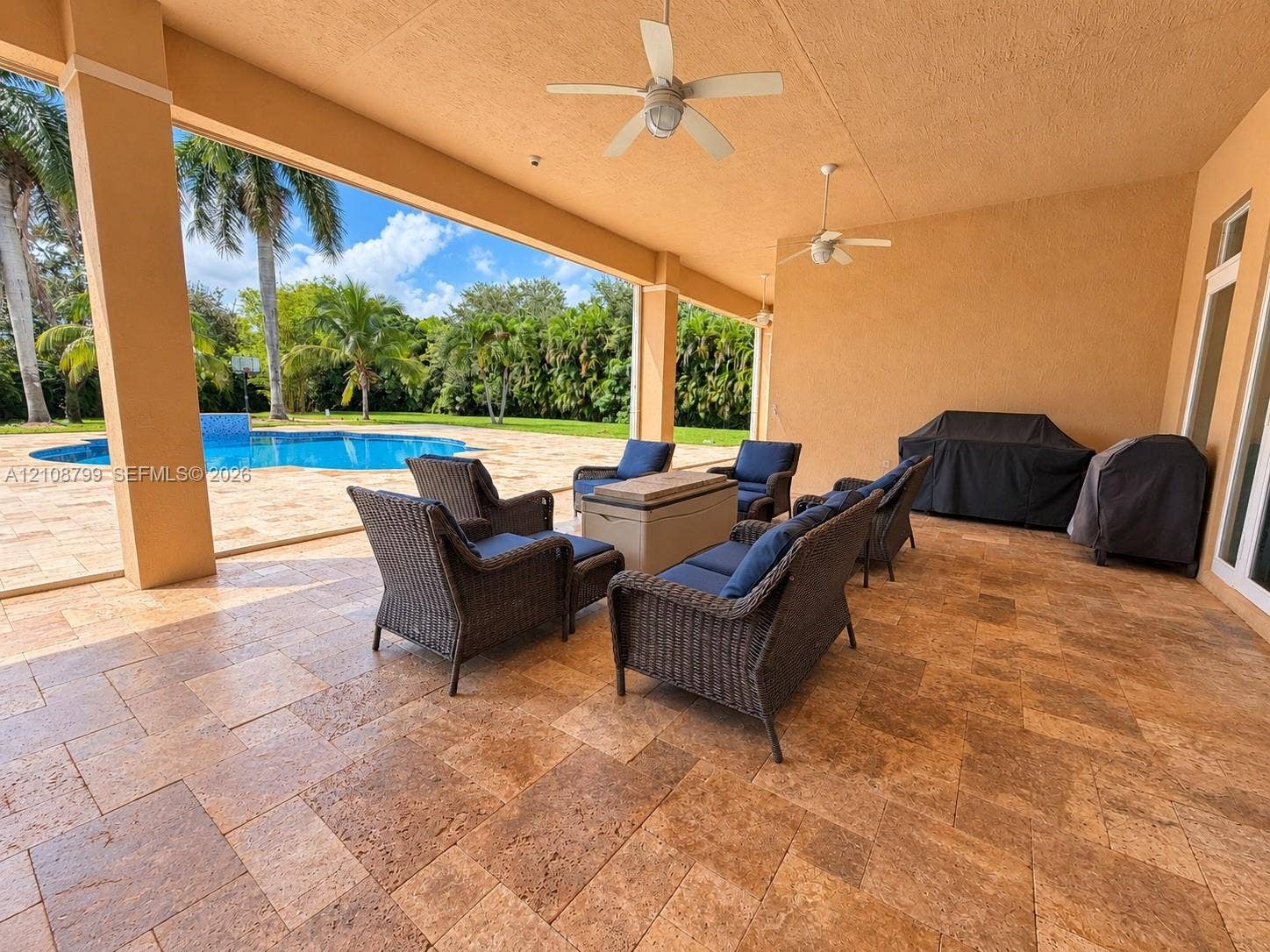 Covered patio featuring stone-tiled flooring, dual ceiling fans, recessed lighting, and a pool deck