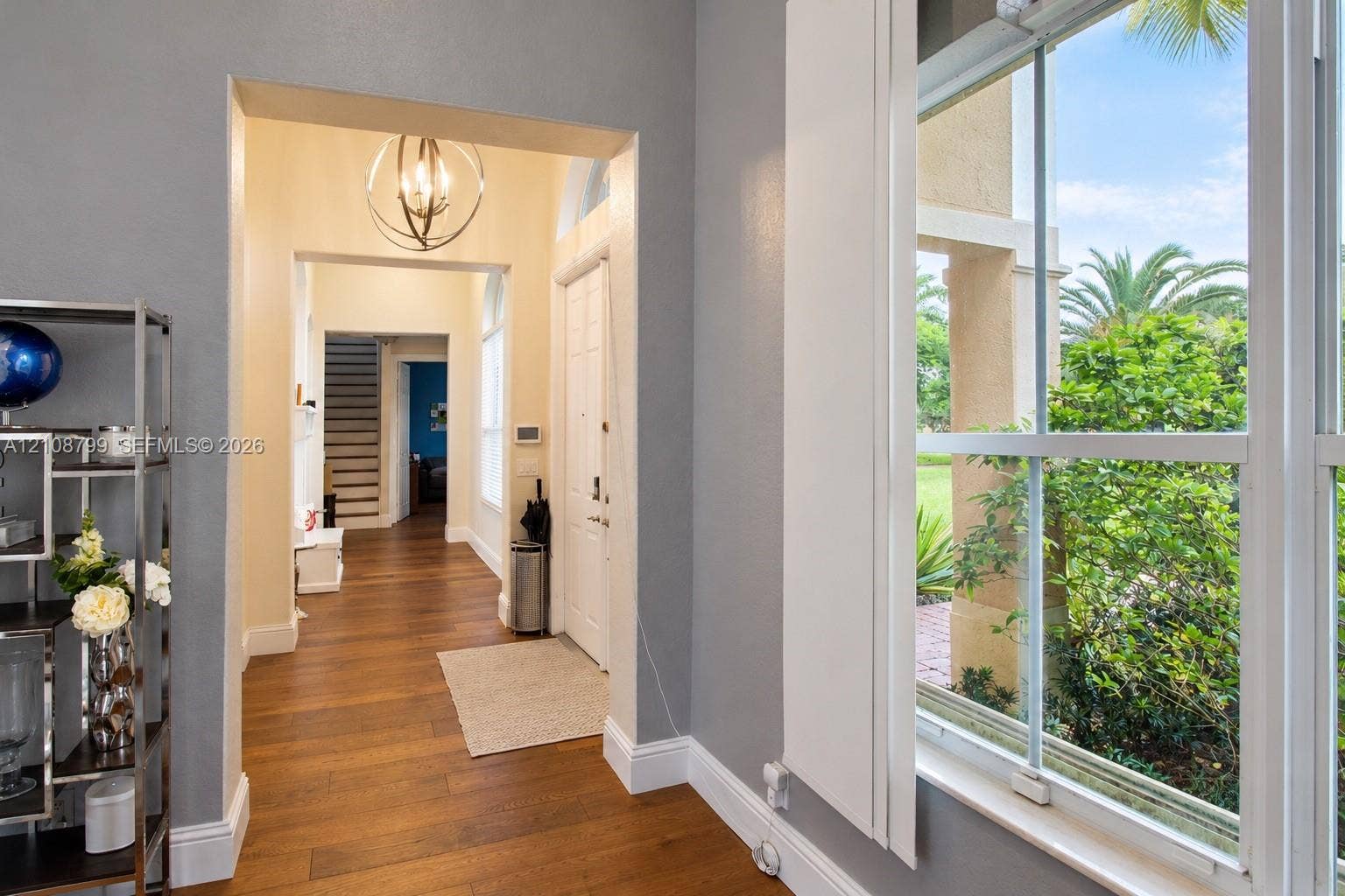 Entryway featuring wood-finish flooring, a multi-pane window, and a spherical orb-style pendant light fixture