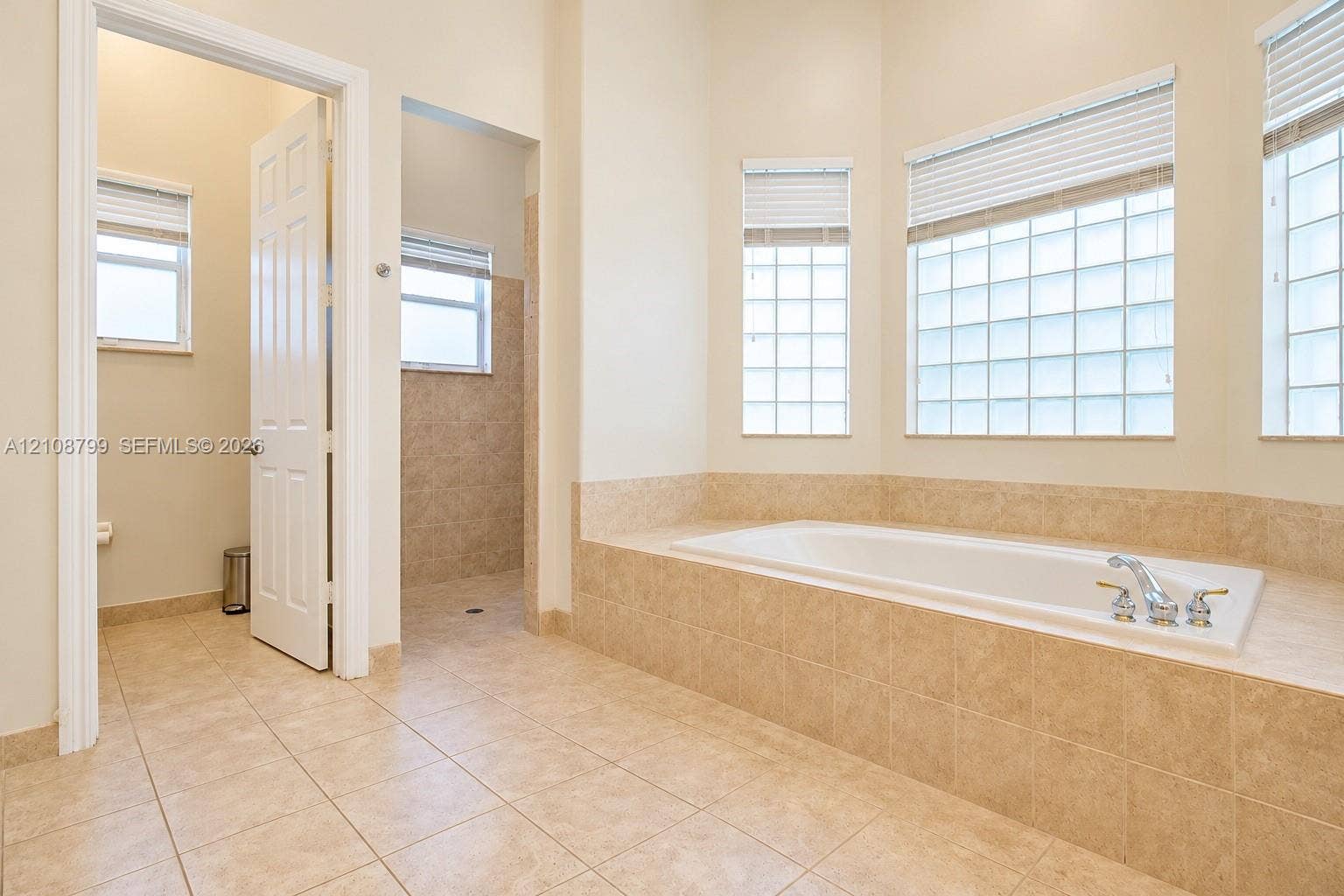 Soaking tub set in a tile-surround deck, tile flooring, glass block windows, and a separate walk-in shower enclosure
