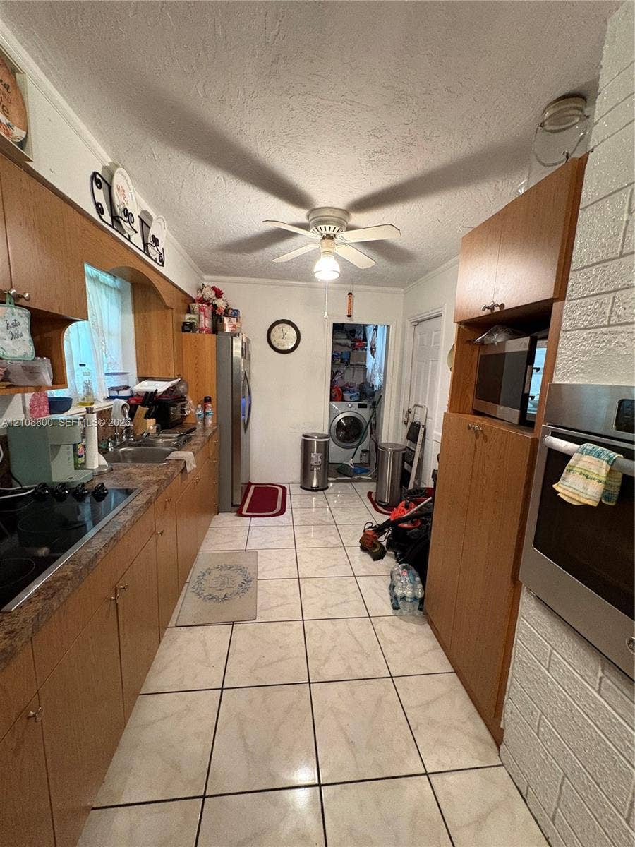451 SW 30th Avenue, Fort Lauderdale, FL 33312 Kitchen featuring wood cabinetry, integrated oven, stone-patterned countertops, tile flooring, and a ceiling-mounted light fixture