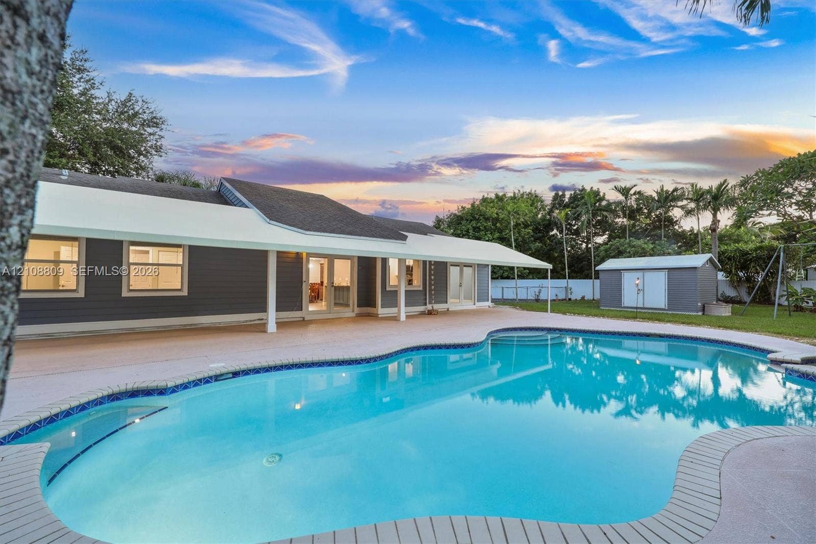 Backyard featuring an in-ground swimming pool, expansive covered patio, and detached storage structure