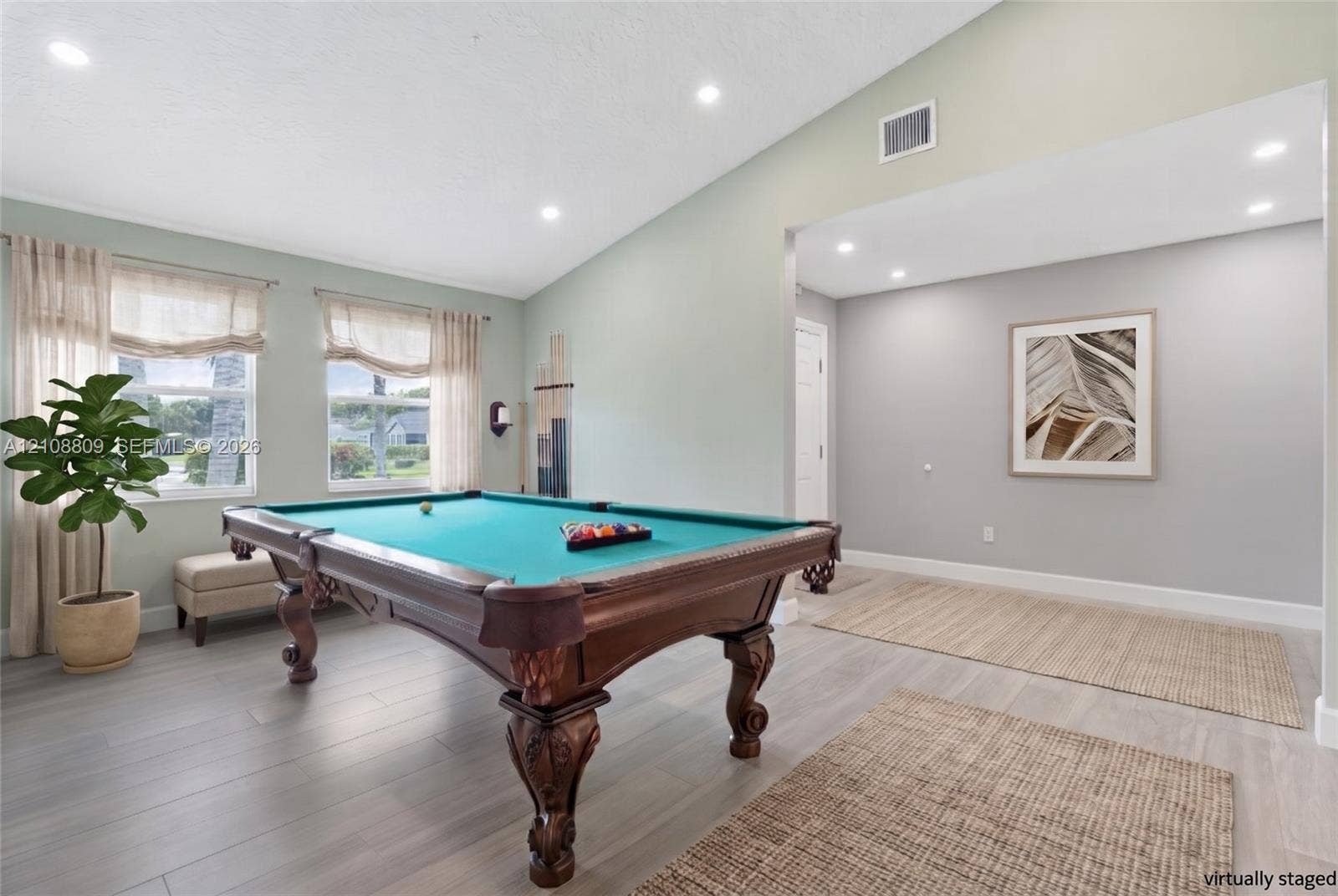 Vaulted ceiling with recessed lighting, wood-finish flooring, and multiple windows
