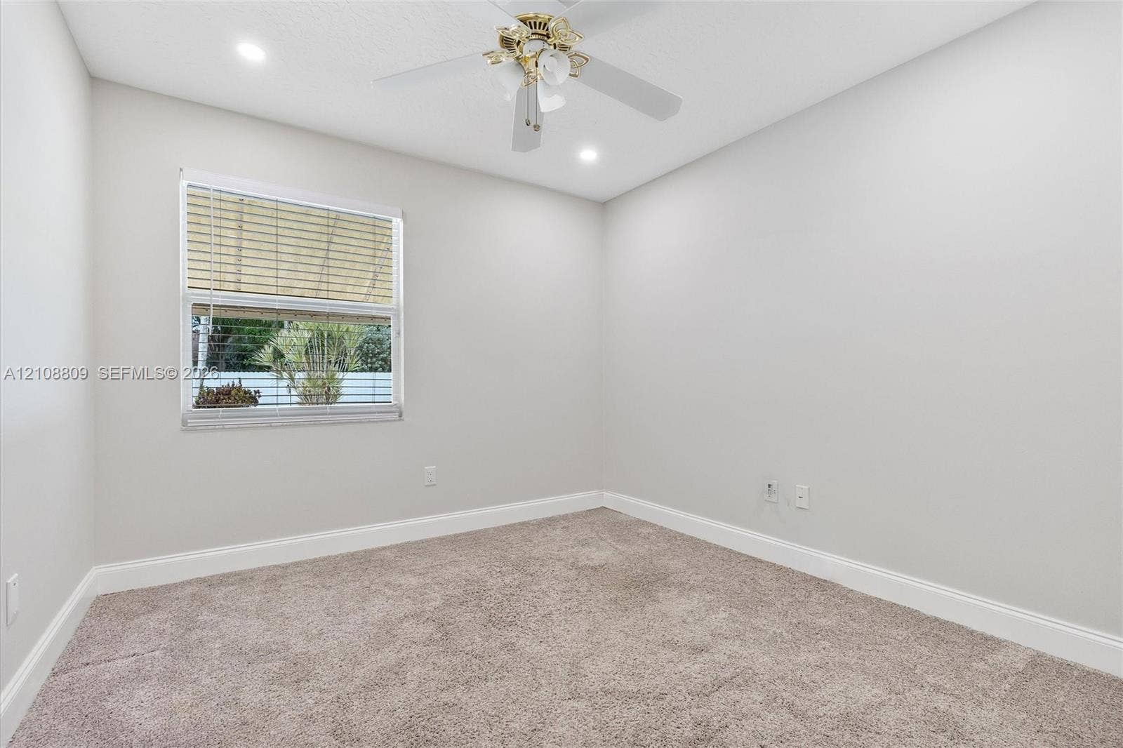 Neutral-toned interior space featuring wall-to-wall carpeting, a single-hung window, and a ceiling fan with integrated lighting