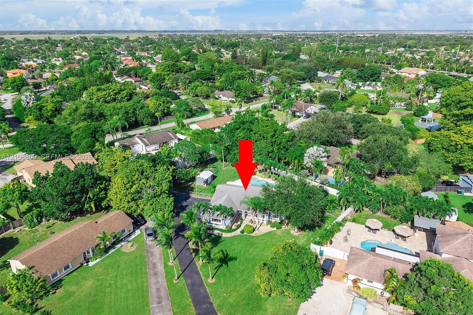 Aerial perspective featuring a multi-pitched roofline, a private swimming pool, and established landscape elements