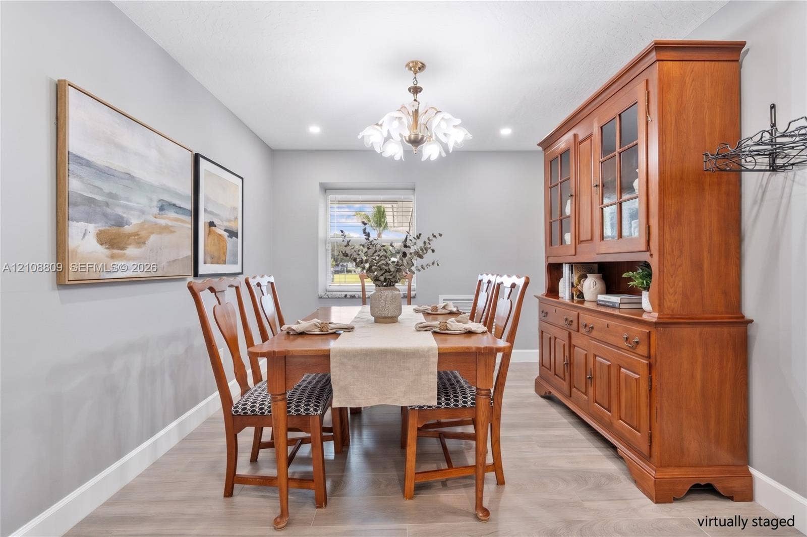 Dining area featuring wood-finish flooring, a multi-bulb floral-style chandelier, and a recessed window