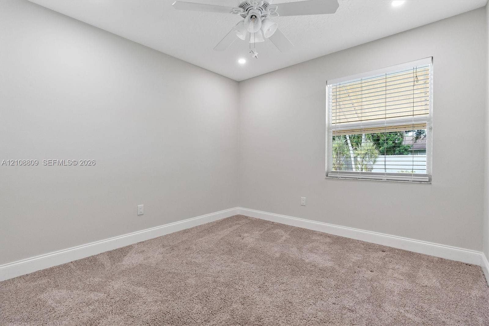 Neutral interior space featuring wall-to-wall carpeting, a ceiling fan with integrated lighting, recessed lighting, and a window with horizontal blinds