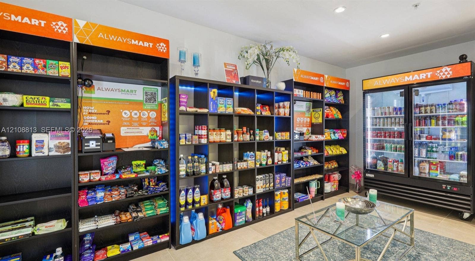 On-site convenience area featuring floor-to-ceiling dark wood shelving units, integrated LED accent lighting, and a commercial-grade double-glass door refrigerator