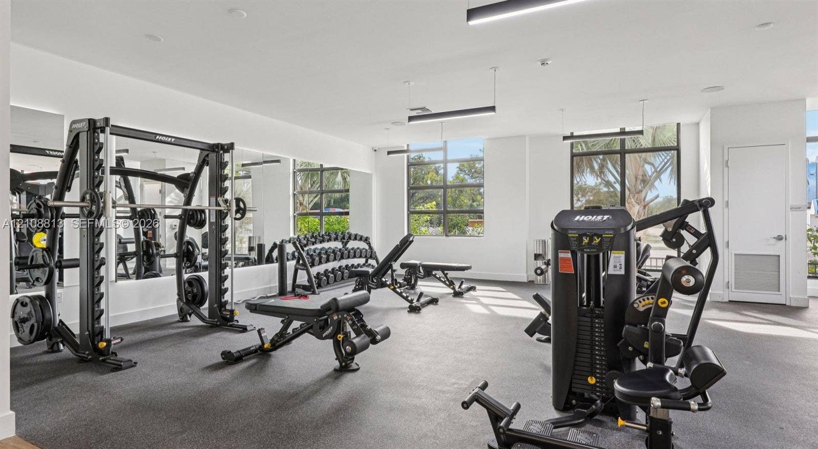 Fitness center featuring rubber flooring, floor-to-ceiling mirrors, industrial-style track lighting, and multi-pane windows