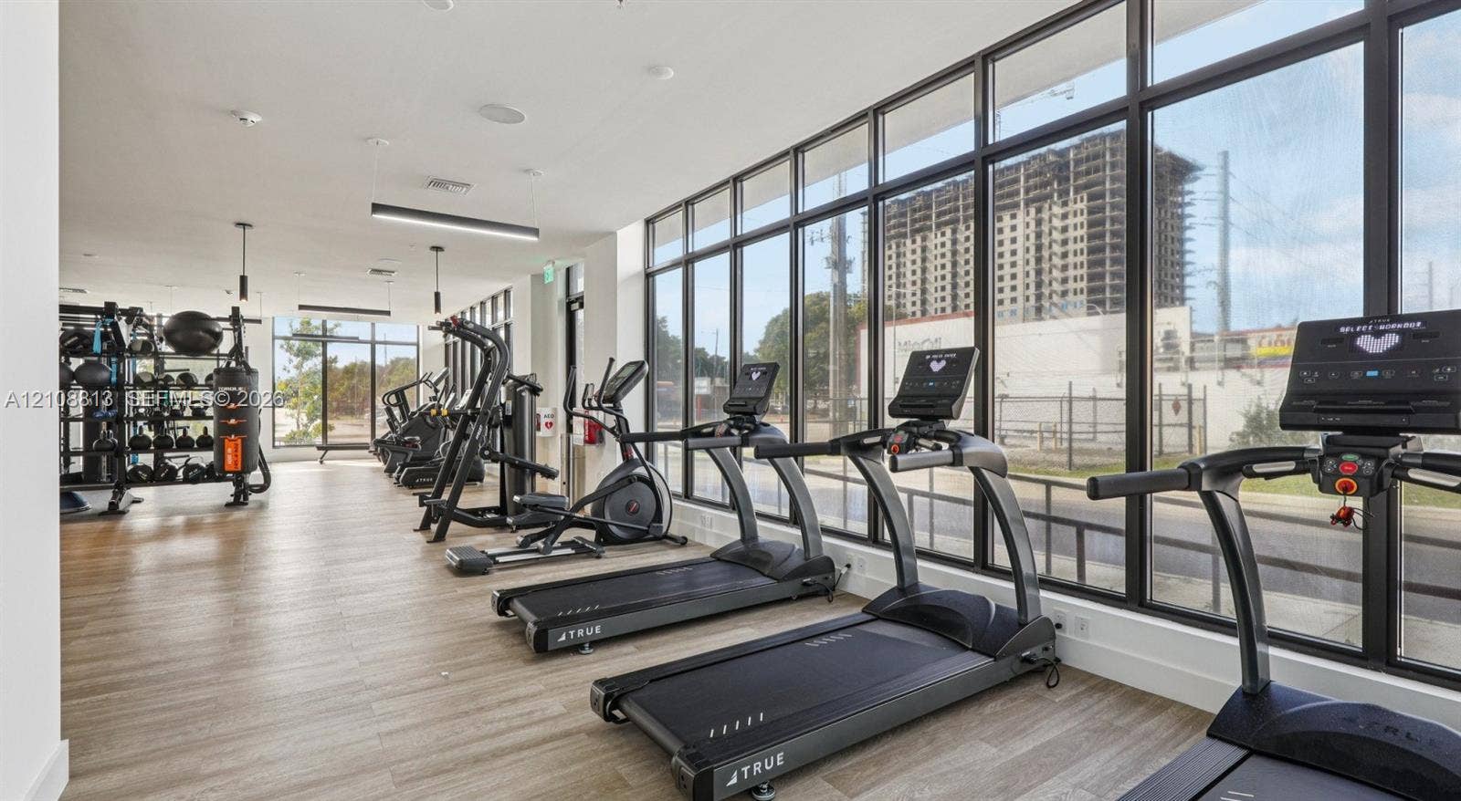 Fitness center featuring floor-to-ceiling windows, wood-finish flooring, and recessed ceiling lighting