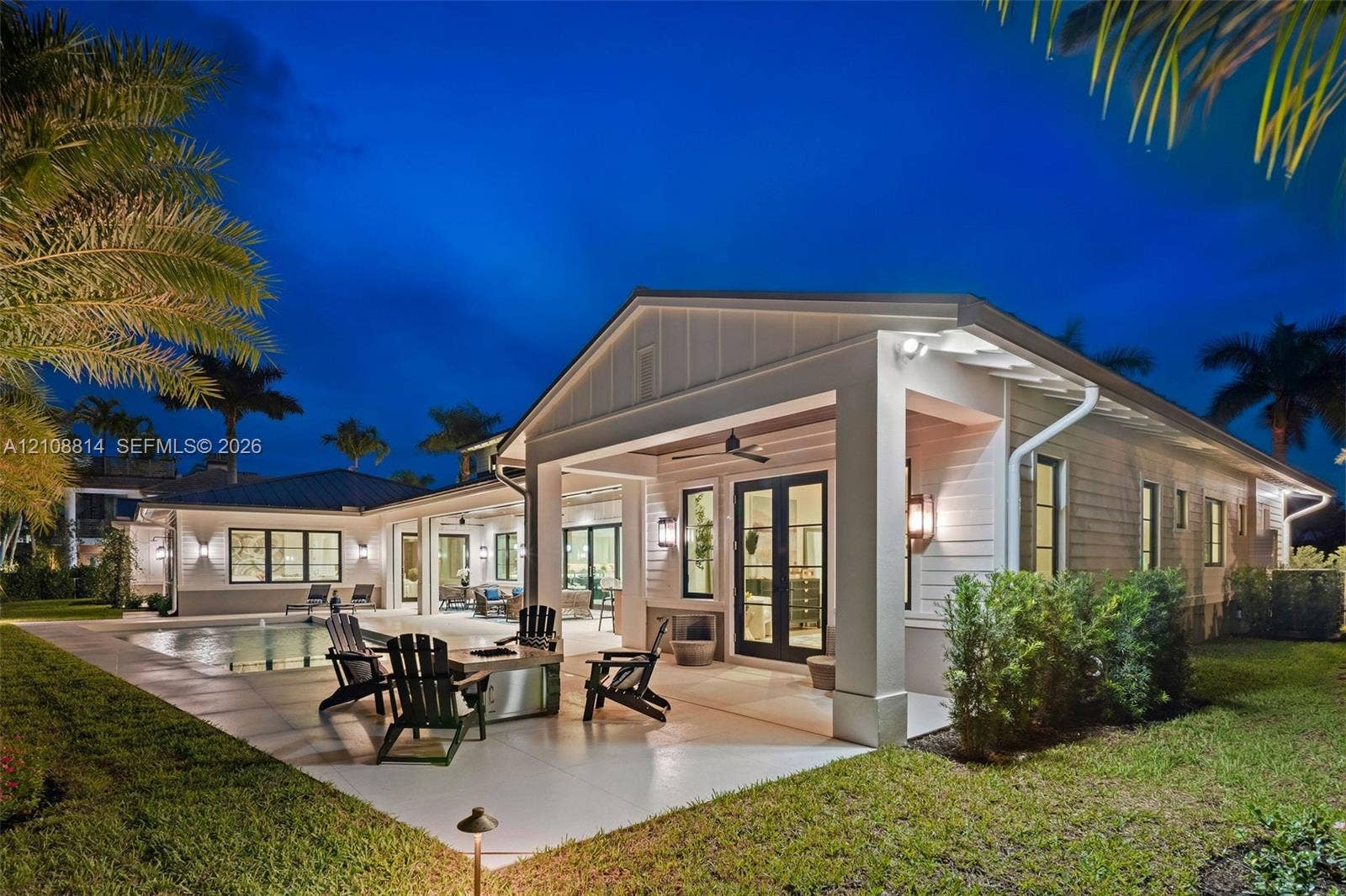 Covered rear terrace featuring a concrete patio, integrated ceiling fan, and wall-mounted exterior lighting, complemented by a swimming pool and board-and-batten siding
