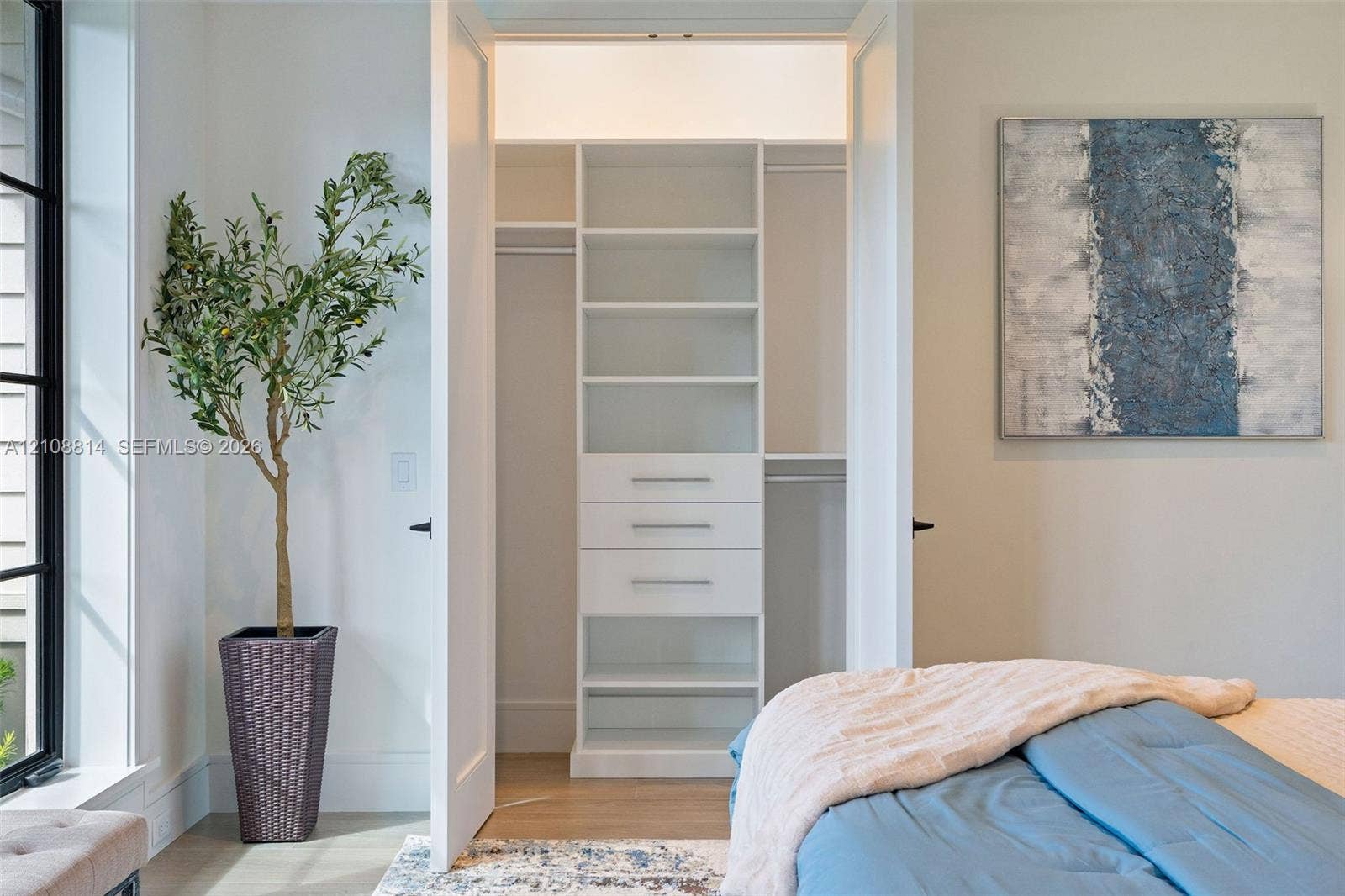 Custom-built closet featuring white cabinetry, tiered shelving, integrated drawers with metallic pulls, and dual hanging rods