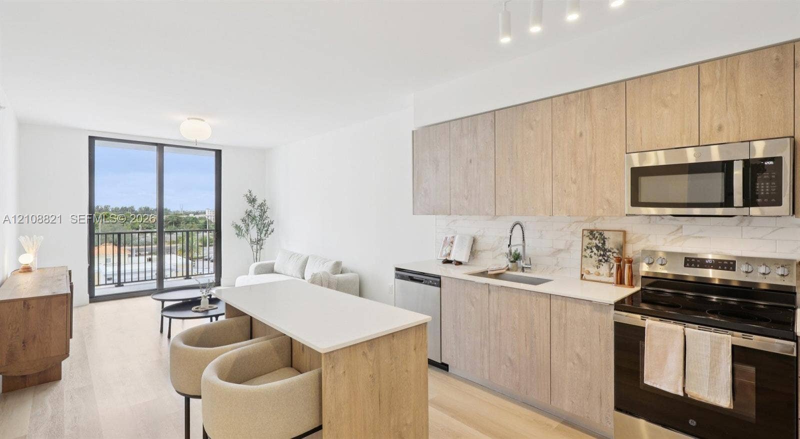 Kitchen featuring light-finish wood cabinetry, a central island with a solid surface countertop, stainless steel appliances, stone-patterned tile backsplash, and wood-finish flooring