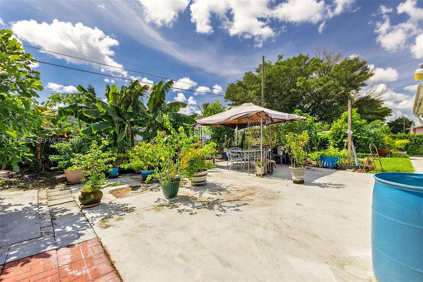 6838 SW 22nd Court, Miramar, FL 33023 Concrete patio featuring decorative red brick edging, mature perimeter landscaping, and established greenery