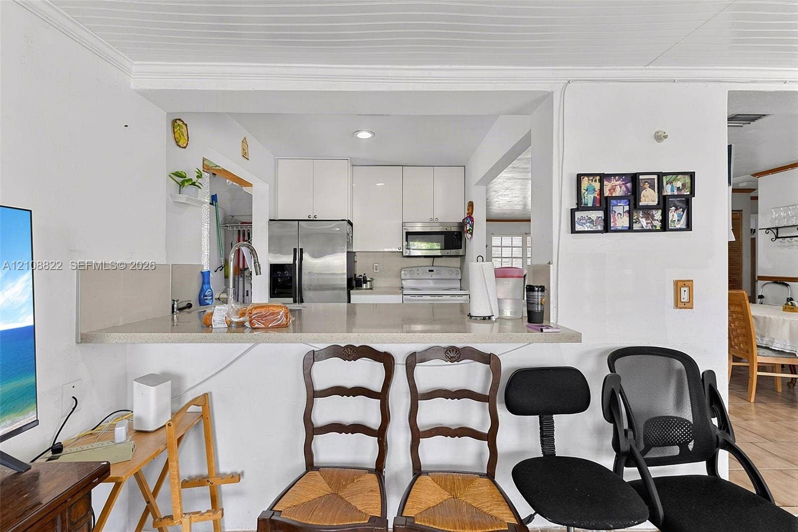 6838 SW 22nd Court, Miramar, FL 33023 Kitchen featuring white cabinetry, a flat-surface countertop with an integrated bar, a stainless steel refrigerator, and a built-in microwave