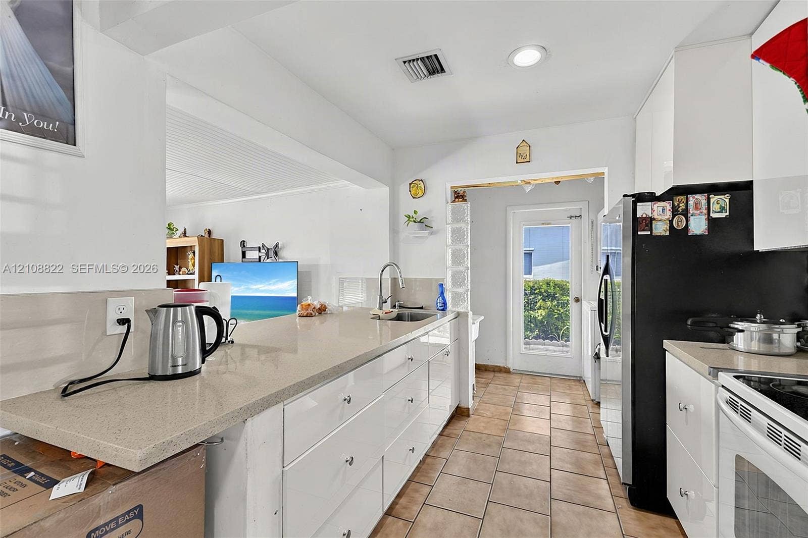 6838 SW 22nd Court, Miramar, FL 33023 Kitchen featuring white flat-panel cabinetry, quartz countertops, tile flooring, and a glass-block framed door