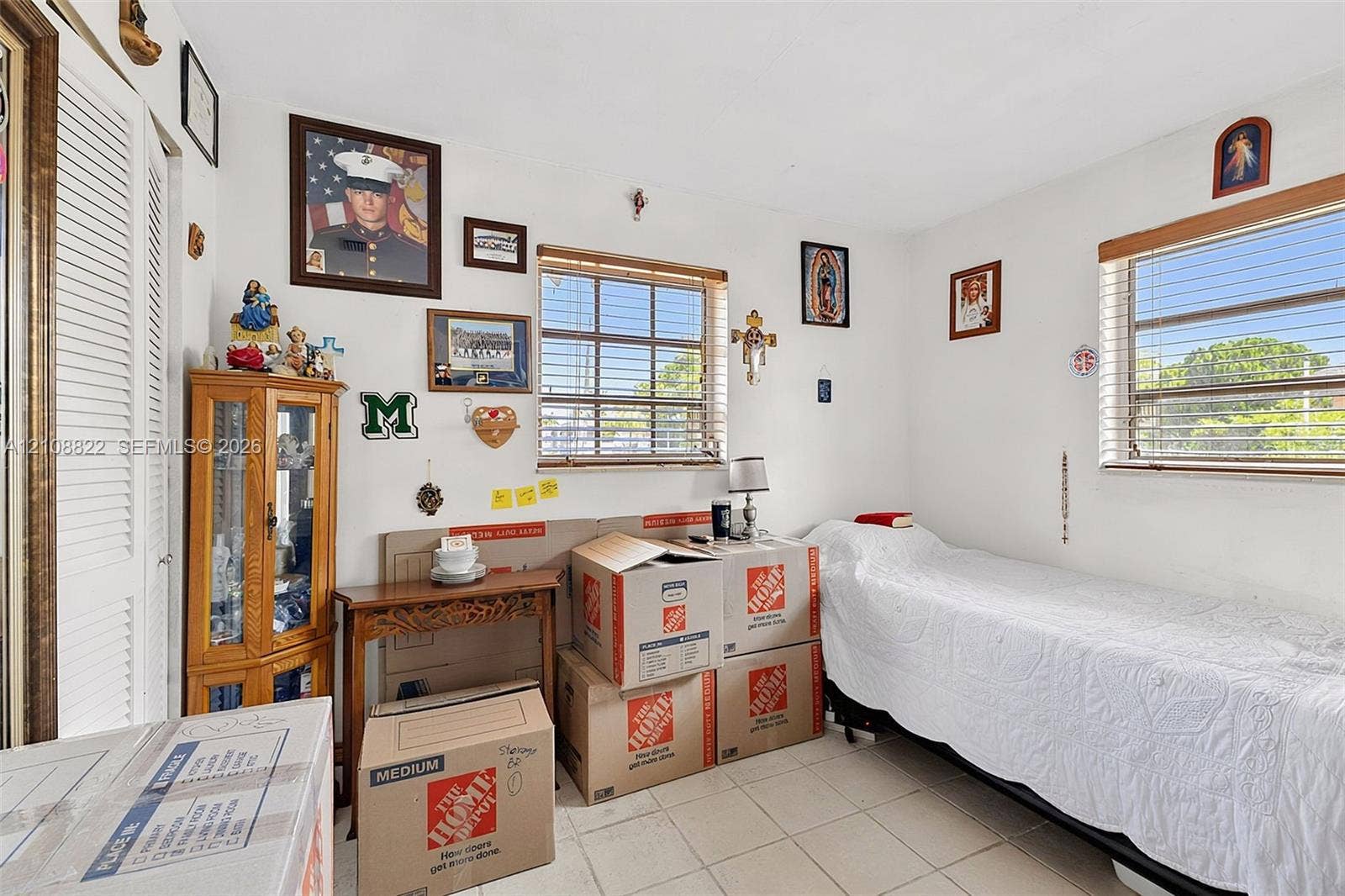 6838 SW 22nd Court, Miramar, FL 33023 Room featuring neutral-toned tile flooring, dual-aspect windows with horizontal blinds, and a floor-to-ceiling built-in corner cabinet with glass-panel doors