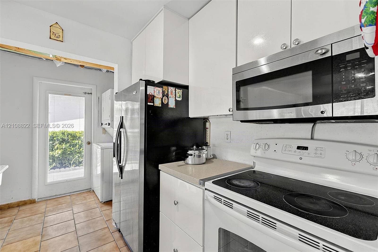 6838 SW 22nd Court, Miramar, FL 33023 Kitchen featuring high-gloss white cabinetry, stone-finish countertops, ceramic tile flooring, and stainless steel and white appliances