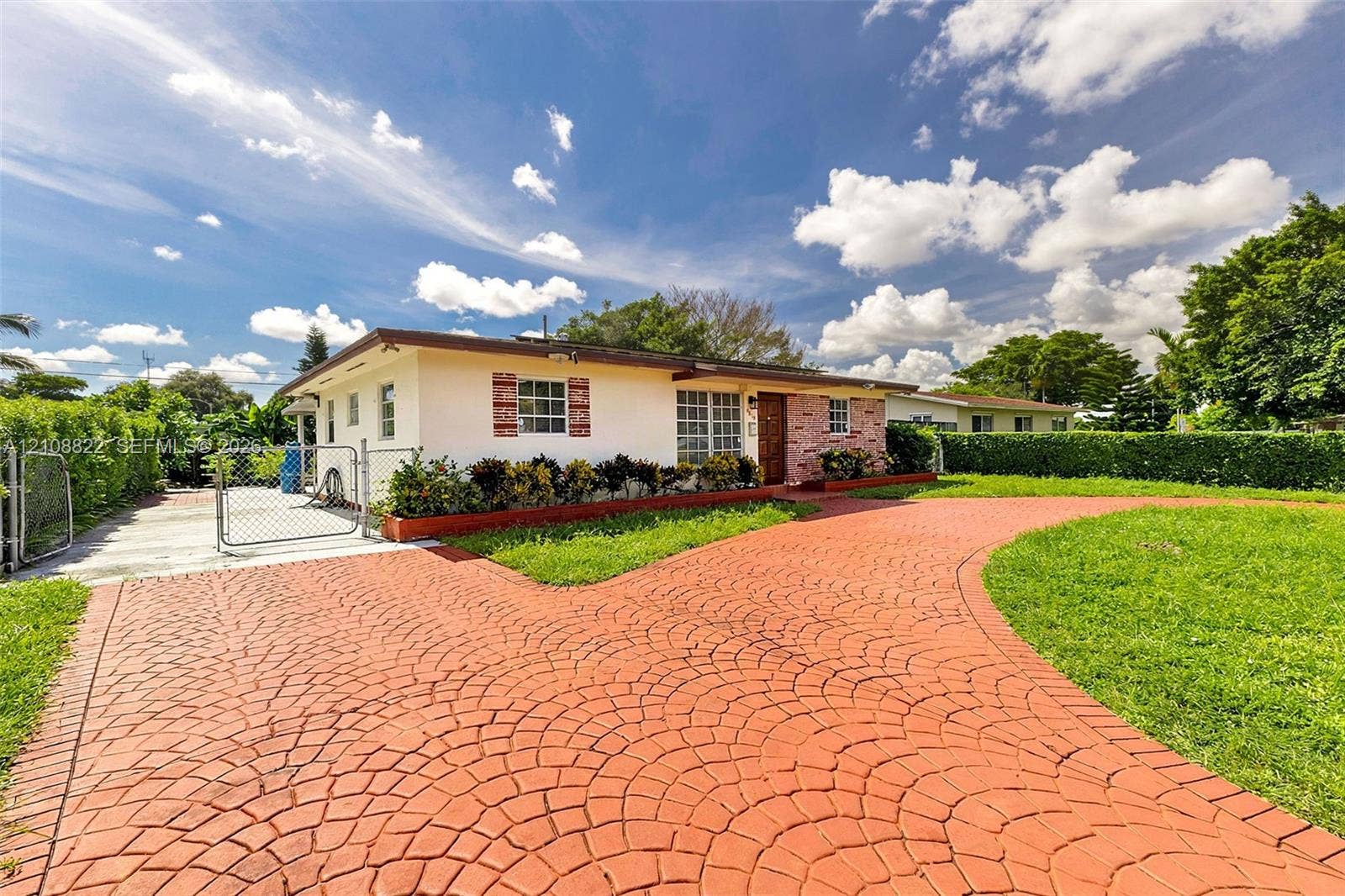 6838 SW 22nd Court, Miramar, FL 33023 Single-story exterior featuring a decorative stamped concrete driveway, exterior brick masonry accents, low-maintenance landscaping, and a chain-link fenced perimeter