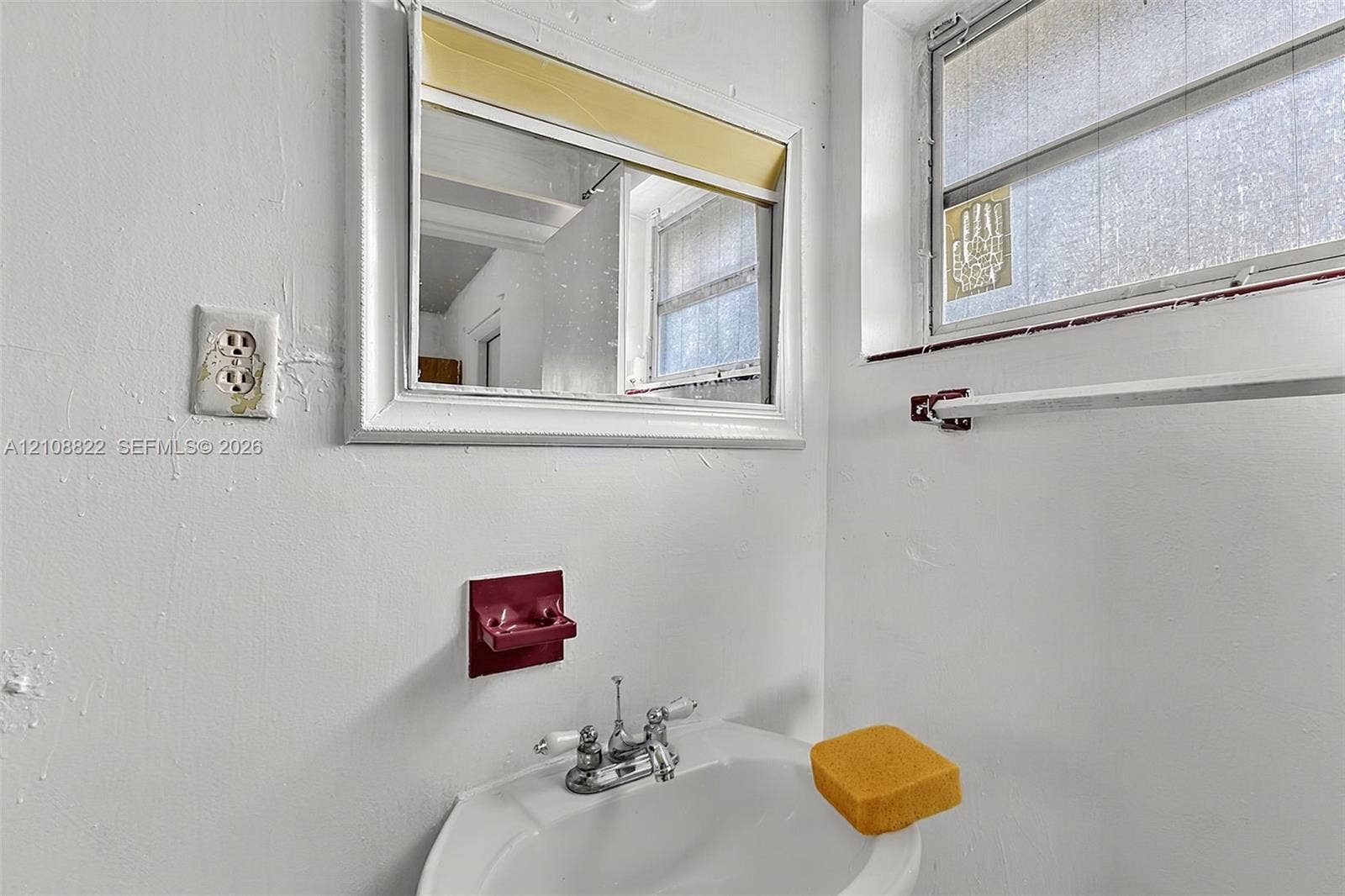 6838 SW 22nd Court, Miramar, FL 33023 Wall-mounted sink basin with a chrome dual-handle faucet, framed wall mirror, and integrated towel bar
