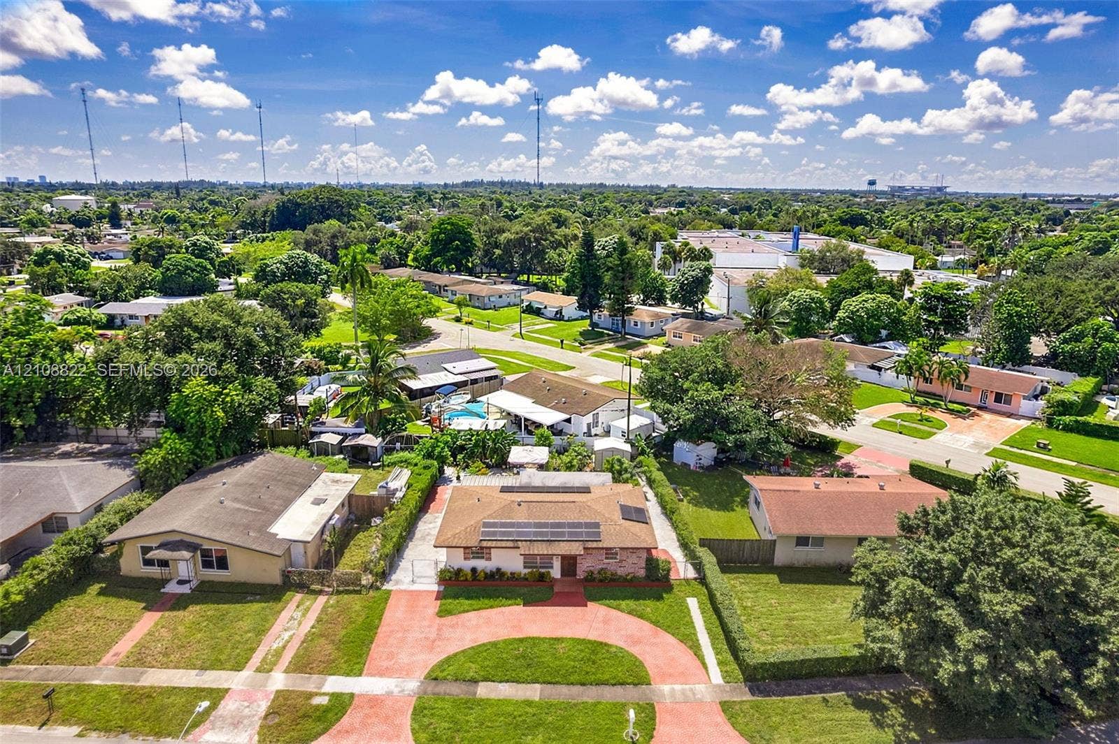 6838 SW 22nd Court, Miramar, FL 33023 Single-story residence featuring a circular paved driveway, solar roof panels, and established landscaping