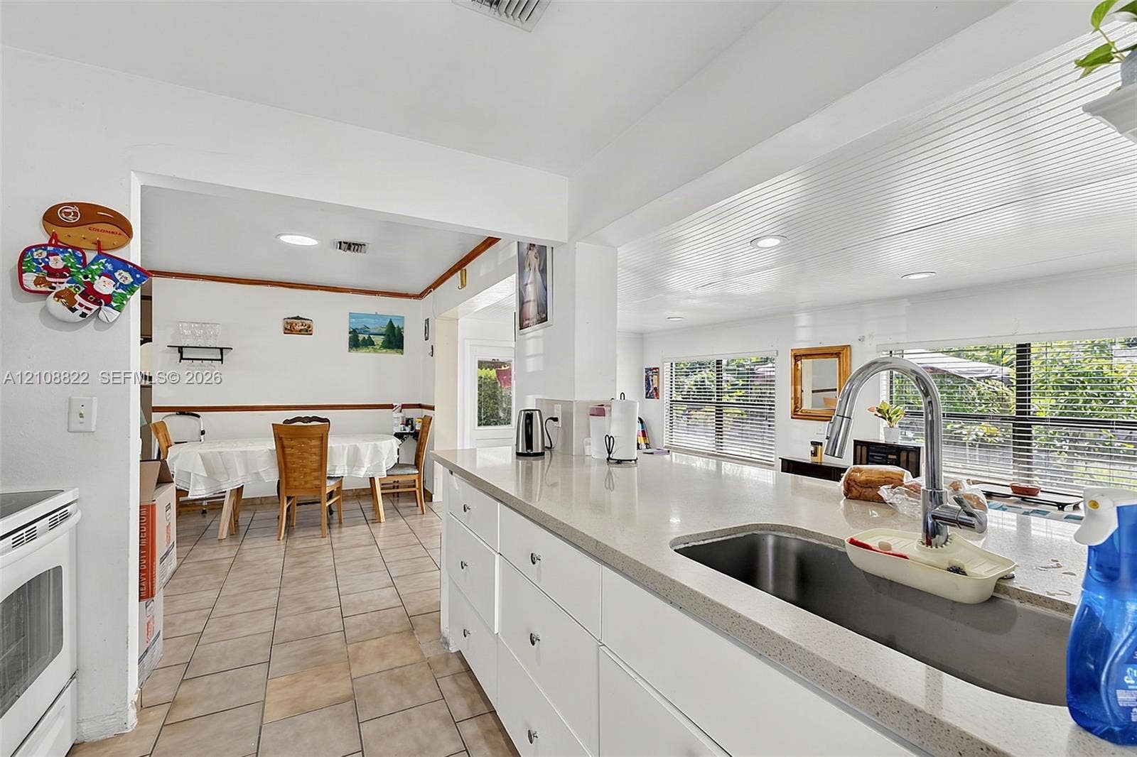 6838 SW 22nd Court, Miramar, FL 33023 Kitchen featuring white cabinetry, solid-surface countertops, an undermount stainless steel sink with a high-arch pull-down faucet, recessed ceiling lighting, and ceramic tile flooring