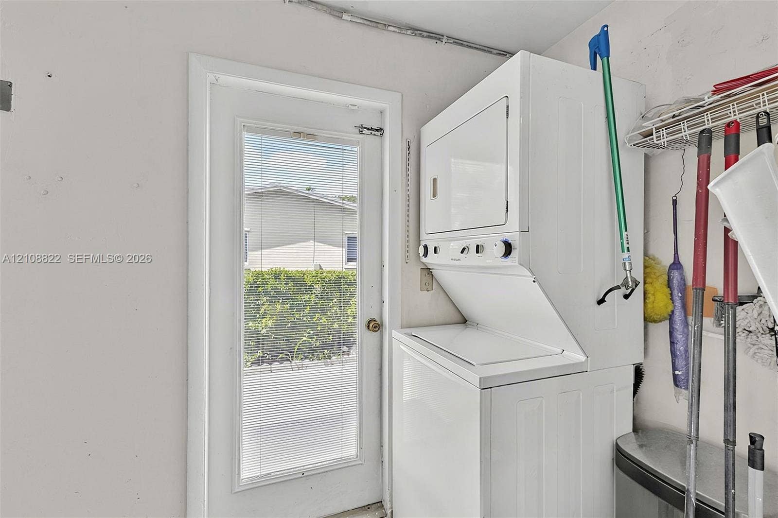 6838 SW 22nd Court, Miramar, FL 33023 Stacked white laundry unit featuring front-loading controls and a full-lite exterior door with integrated blinds