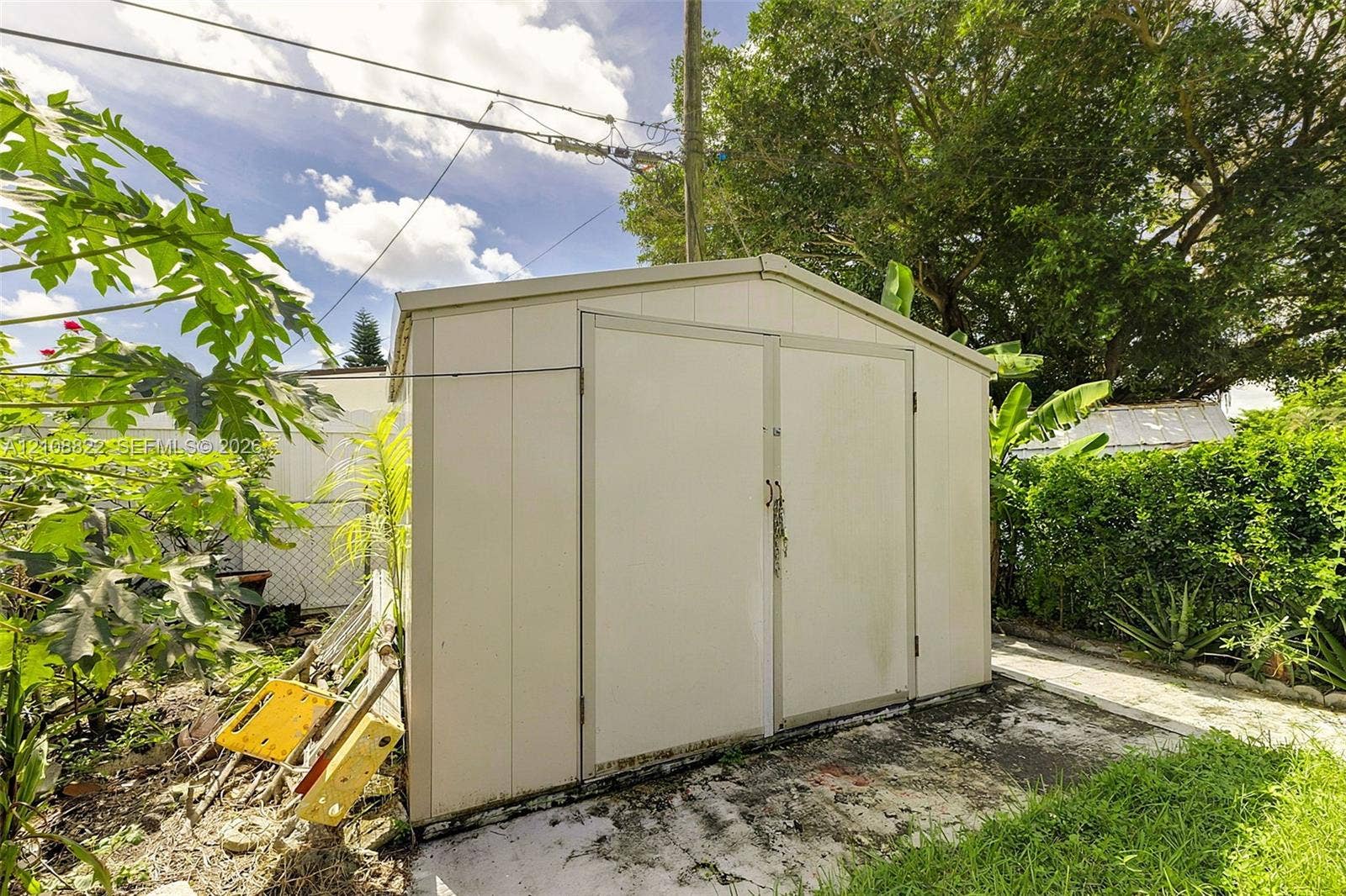 6838 SW 22nd Court, Miramar, FL 33023 Detached metal storage structure featuring double doors and a gable roof, positioned on a concrete pad within the backyard
