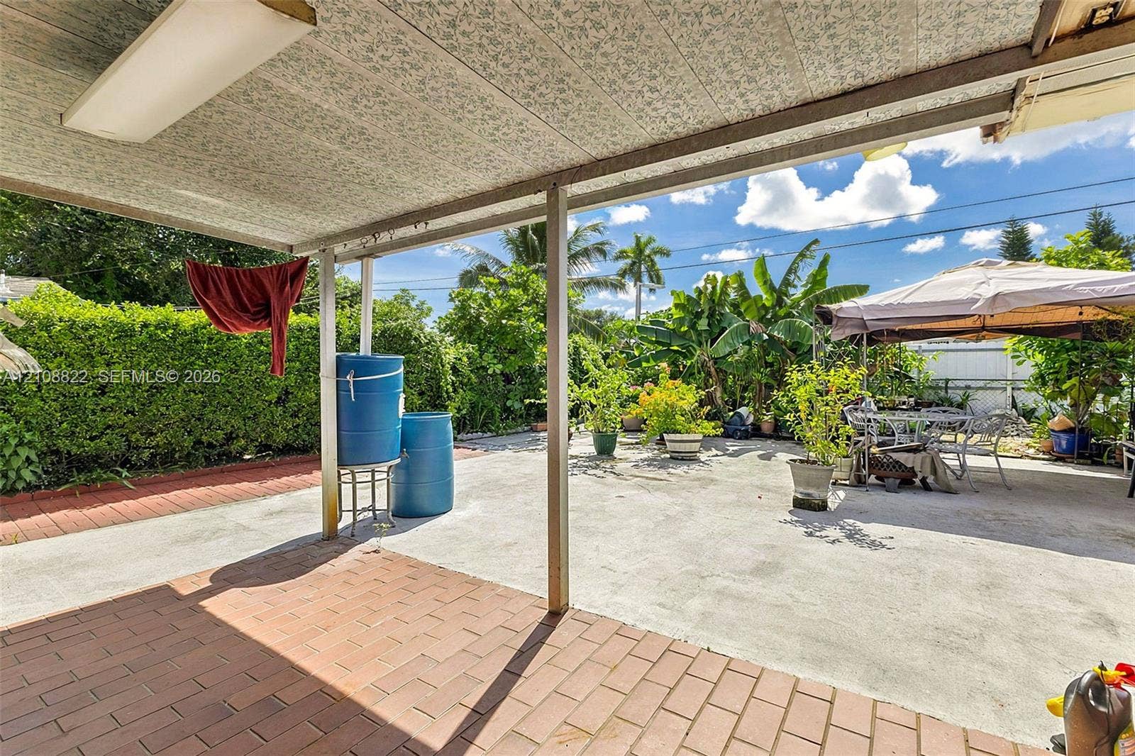 6838 SW 22nd Court, Miramar, FL 33023 Covered patio area with brick-style paver flooring, concrete surface, and mature perimeter landscaping