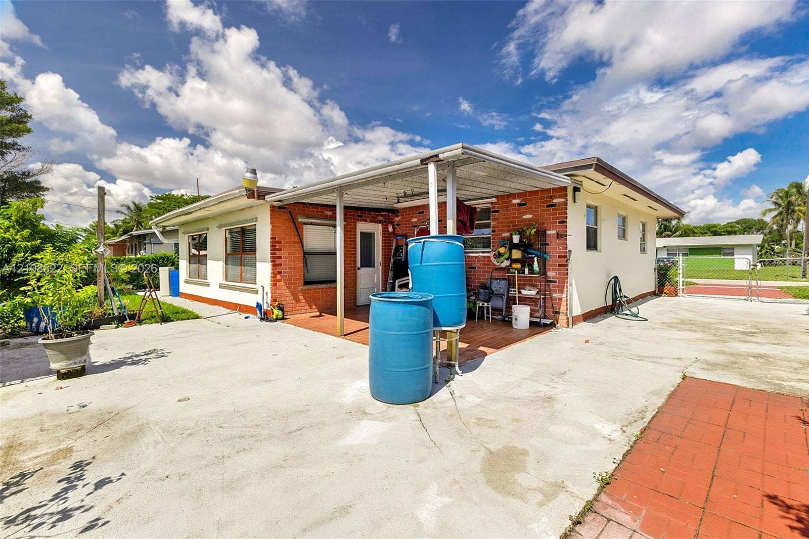 6838 SW 22nd Court, Miramar, FL 33023 Single-story residence featuring a brick and stucco exterior, covered patio, concrete driveway, and gated perimeter