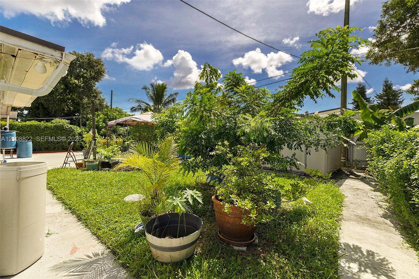 6838 SW 22nd Court, Miramar, FL 33023 Outdoor space featuring a concrete patio, grassy lawn, mature greenery, and perimeter hedging