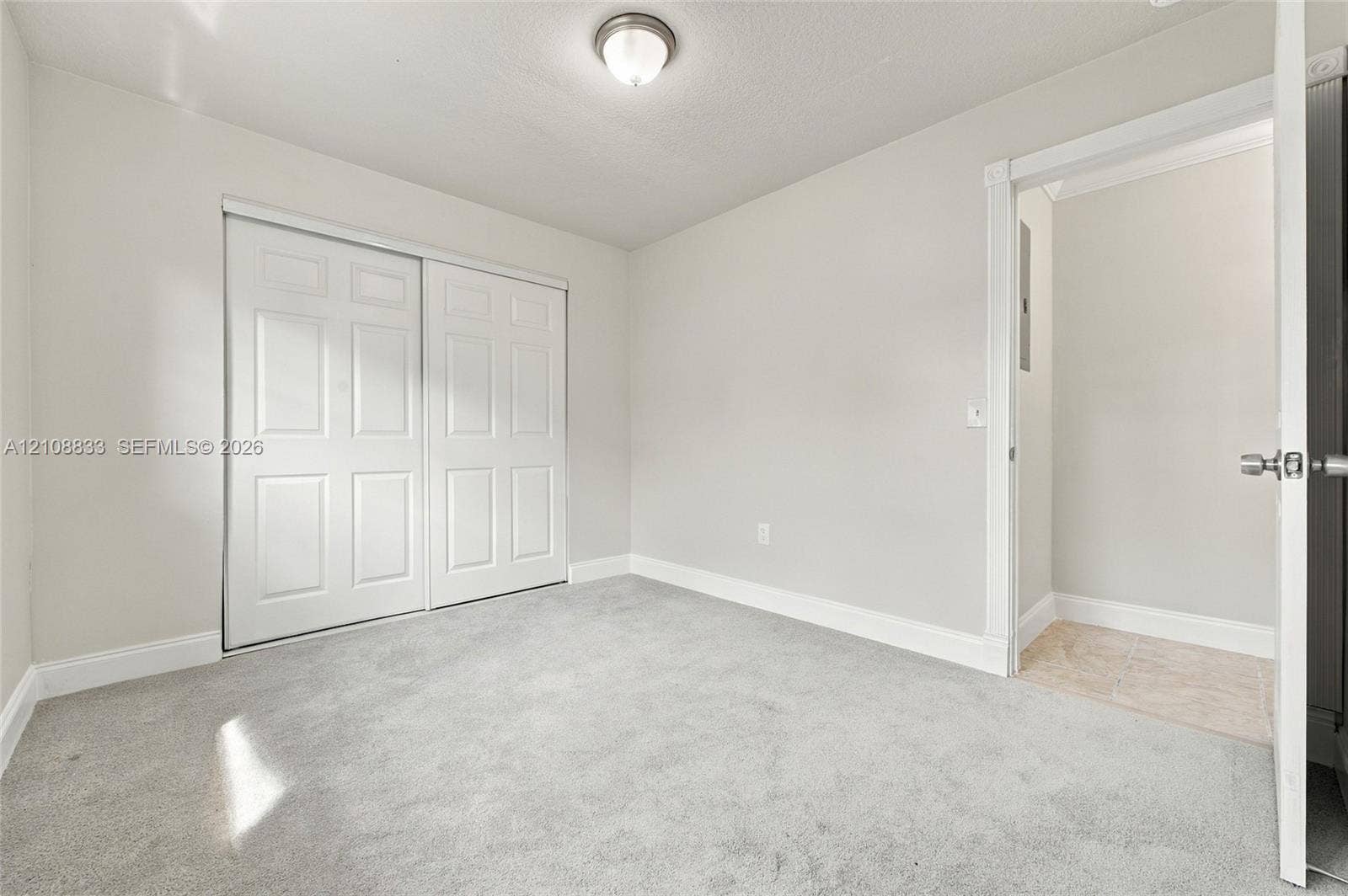 9611 Johnson Street, Pembroke Pines, FL 33024 Neutral-toned carpeting, sliding panel closet doors, ceiling-mounted flush light fixture, and interior door with brushed metal hardware