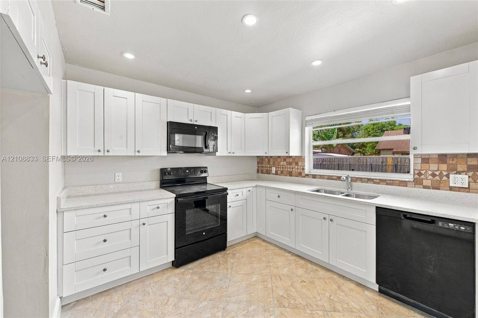 9611 Johnson Street, Pembroke Pines, FL 33024 Kitchen featuring white cabinetry, solid surface countertops, a tiled backsplash, black built-in appliances, and recessed lighting
