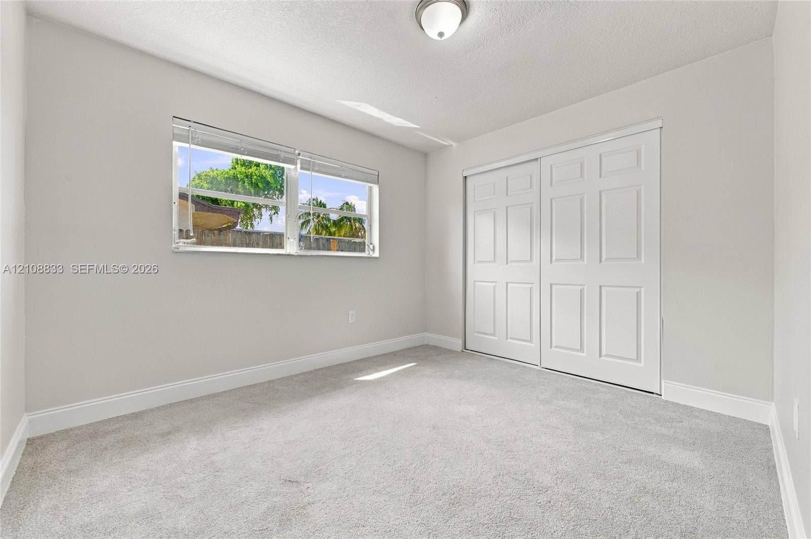 9611 Johnson Street, Pembroke Pines, FL 33024 Neutral-toned carpeting, white six-panel closet doors, ceiling-mounted lighting, and a window with horizontal blinds