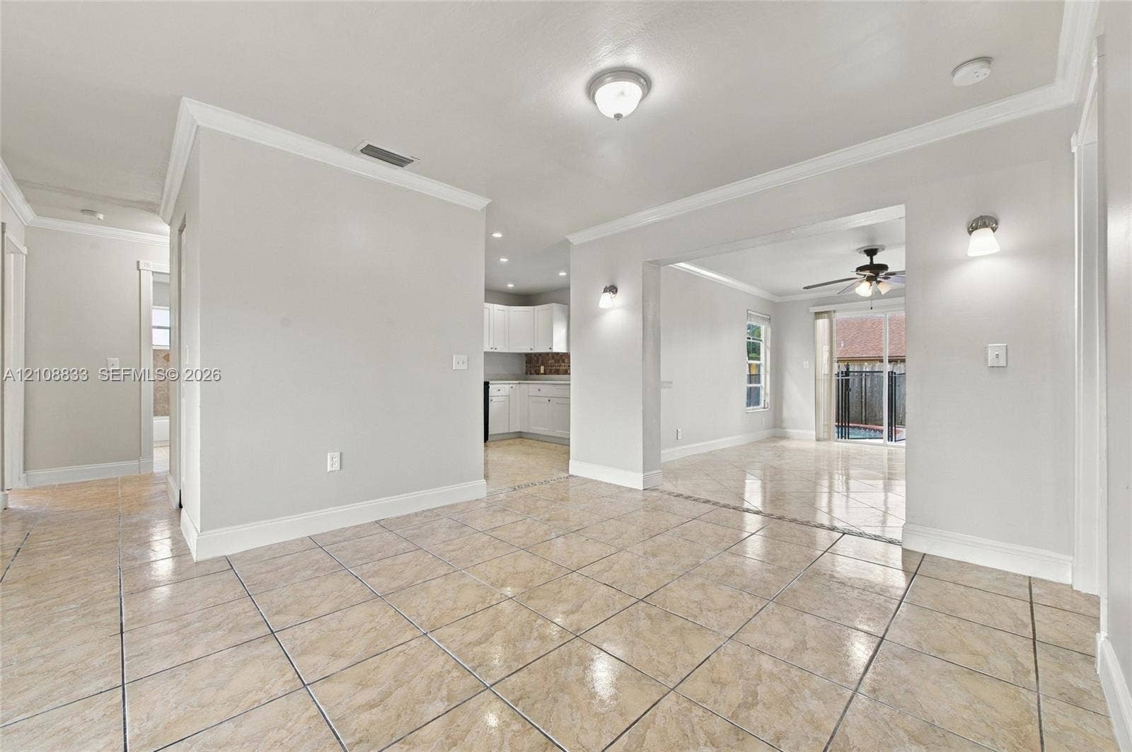 9611 Johnson Street, Pembroke Pines, FL 33024 Interior featuring large-format tile flooring, crown molding, wall-mounted light fixtures, and a glass sliding door