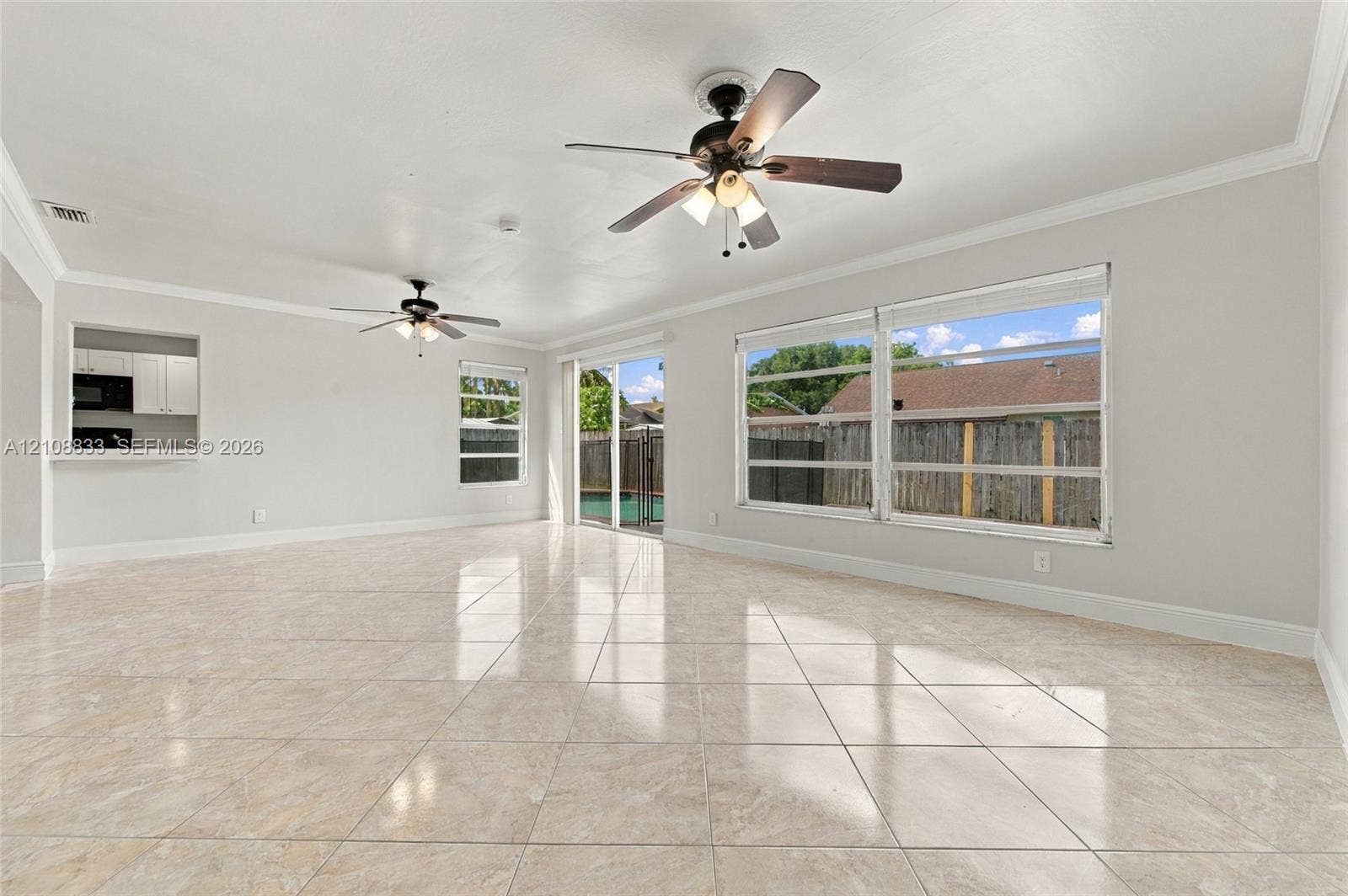 9611 Johnson Street, Pembroke Pines, FL 33024 Interior space featuring large-format tile flooring, two ceiling fans with integrated light kits, crown molding, and sliding glass doors
