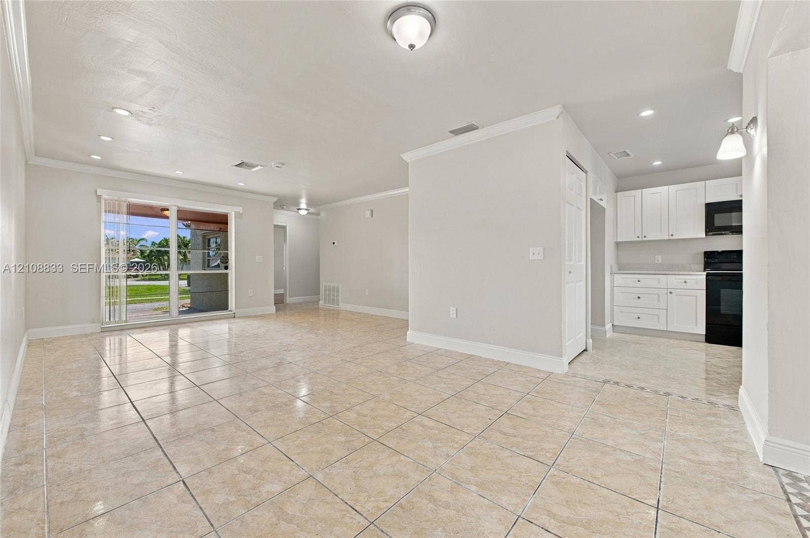 9611 Johnson Street, Pembroke Pines, FL 33024 Open interior featuring neutral tile flooring, crown molding, recessed lighting, and a kitchen equipped with white cabinetry and built-in appliances