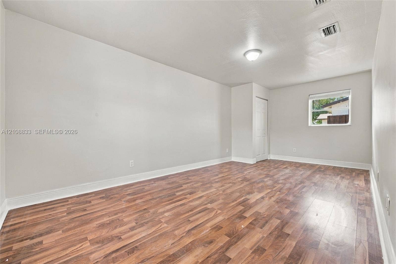 9611 Johnson Street, Pembroke Pines, FL 33024 Interior room featuring wood-finish flooring, a single-pane window, flush-mount ceiling lighting, and a paneled closet door