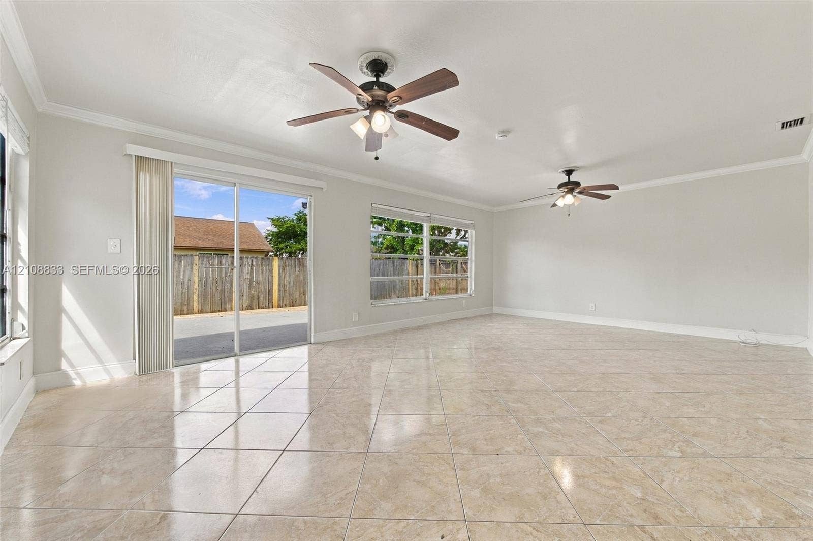 9611 Johnson Street, Pembroke Pines, FL 33024 Spacious room featuring large-format tile flooring, dual ceiling fans with integrated lighting, and sliding glass doors
