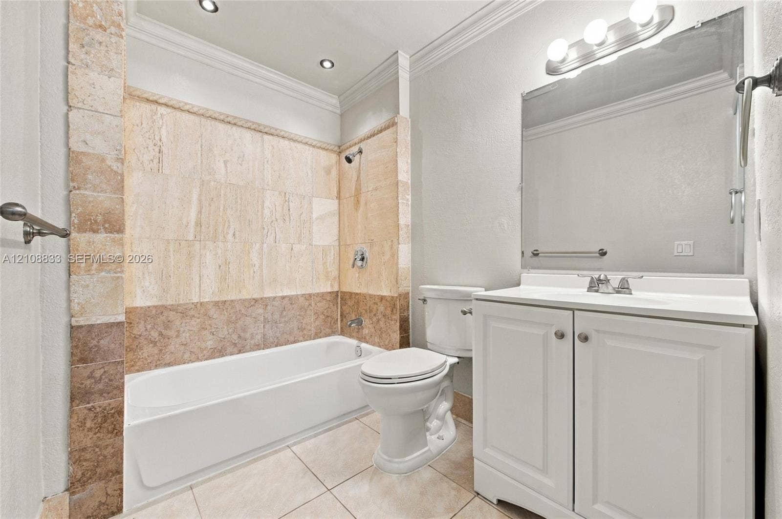 9611 Johnson Street, Pembroke Pines, FL 33024 Bathroom featuring a tub-shower combination with multi-toned stone tile surround, vanity with cabinetry, large-format mirror, and crown molding
