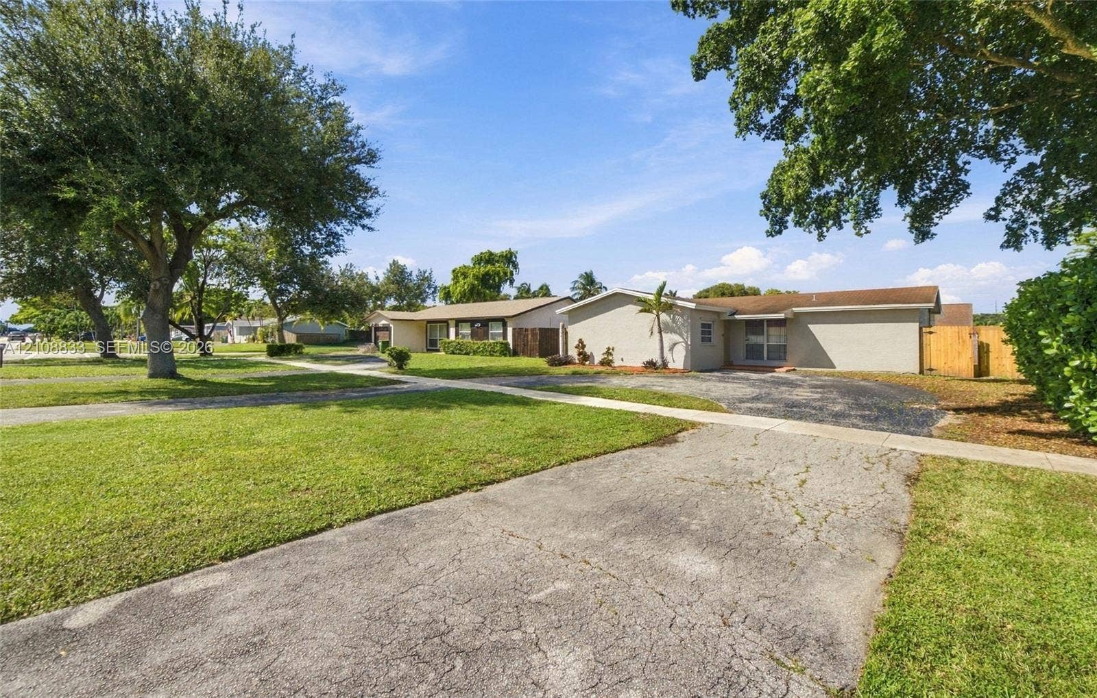 9611 Johnson Street, Pembroke Pines, FL 33024 Single-story exterior featuring a stucco facade, expansive front lawn, mature trees, and a paved driveway