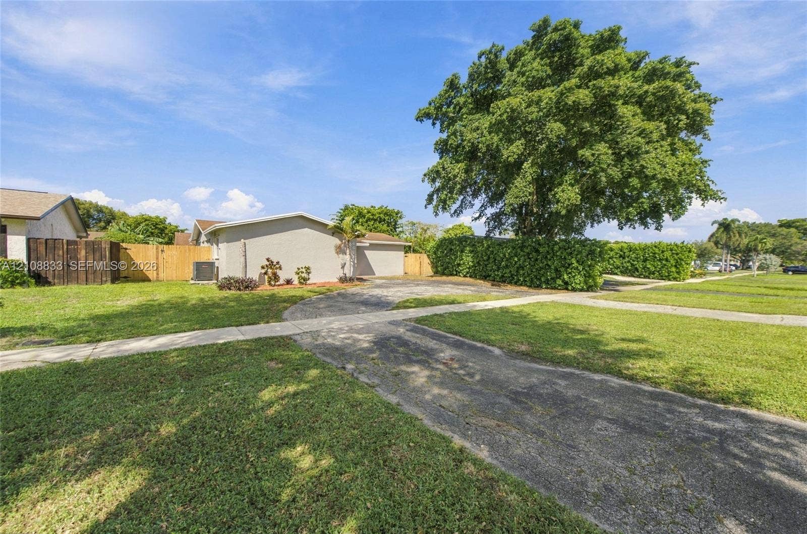 9611 Johnson Street, Pembroke Pines, FL 33024 Exterior featuring a concrete driveway, mature landscaping, and a wood privacy fence