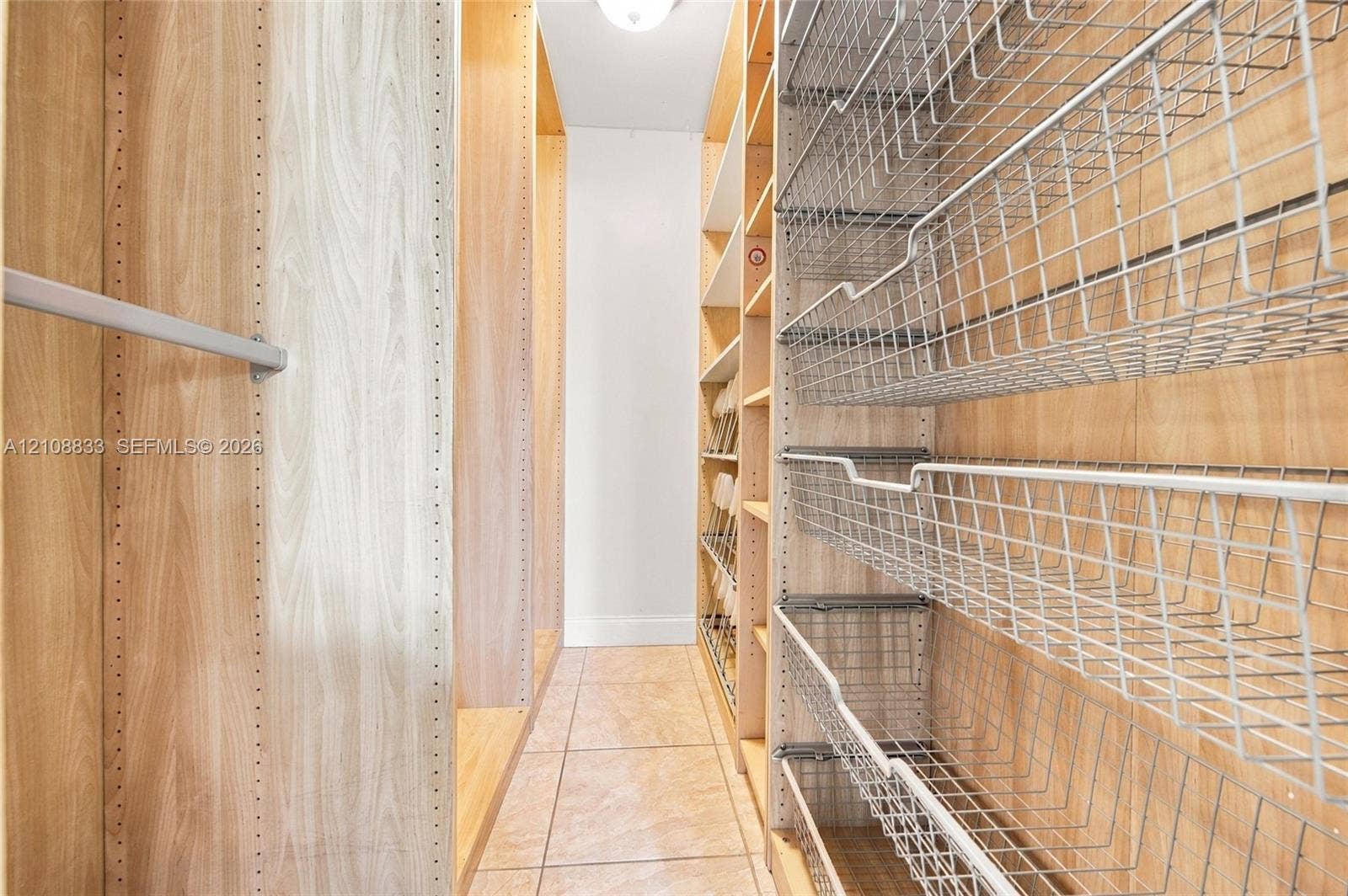 9611 Johnson Street, Pembroke Pines, FL 33024 Custom storage system featuring light wood-finish shelving, integrated metal pull-out wire baskets, adjustable hanging rods, and tile flooring