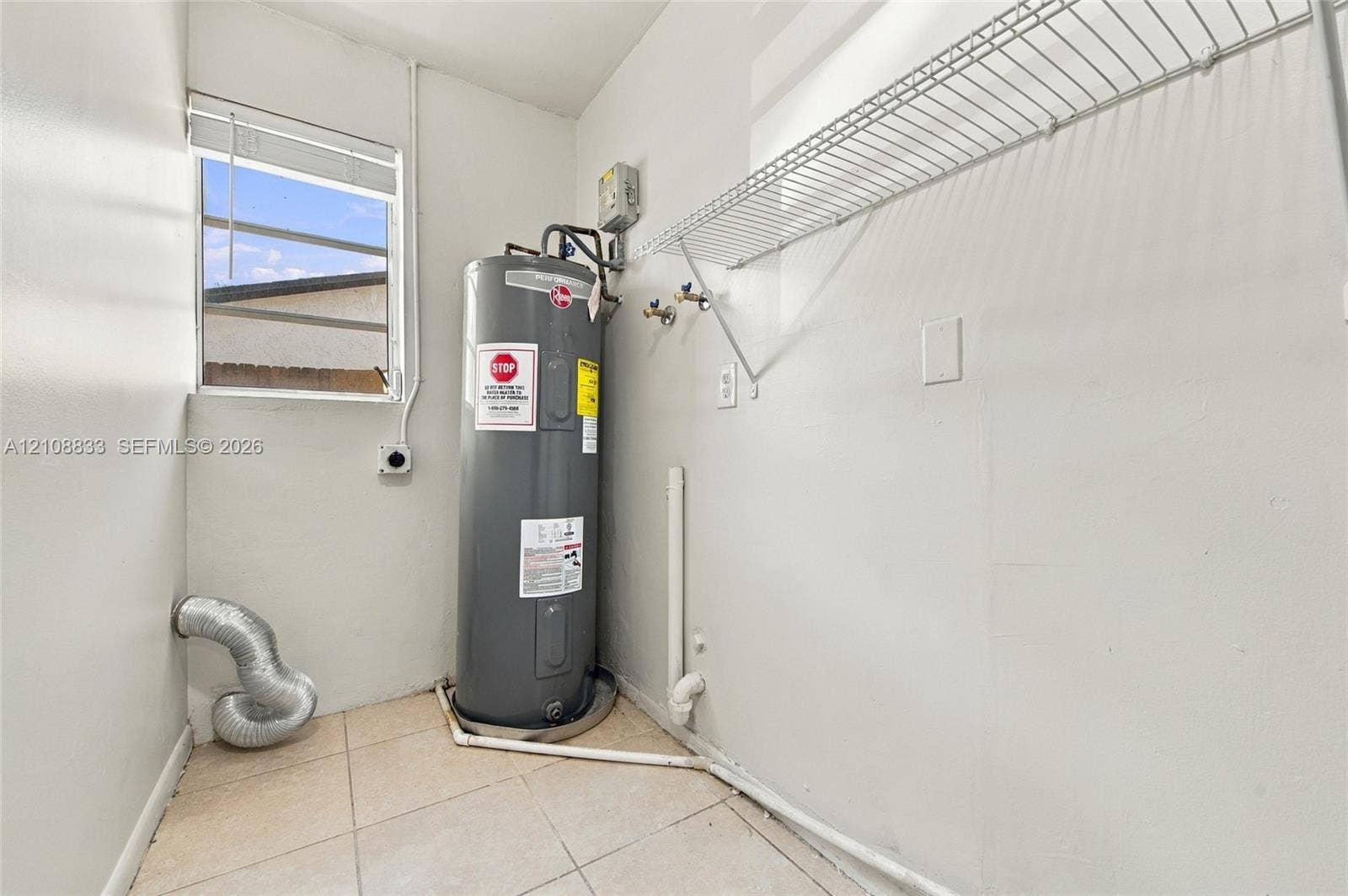 9611 Johnson Street, Pembroke Pines, FL 33024 Utility area featuring tile flooring, a window, wall-mounted wire shelving, and a water heater
