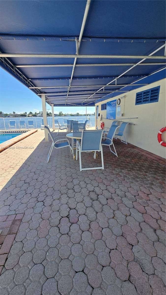 3000 Marcos Drive, #P304, Aventura, FL 33160 Covered outdoor patio featuring concrete paver flooring, a retractable fabric awning, and perimeter metal fencing