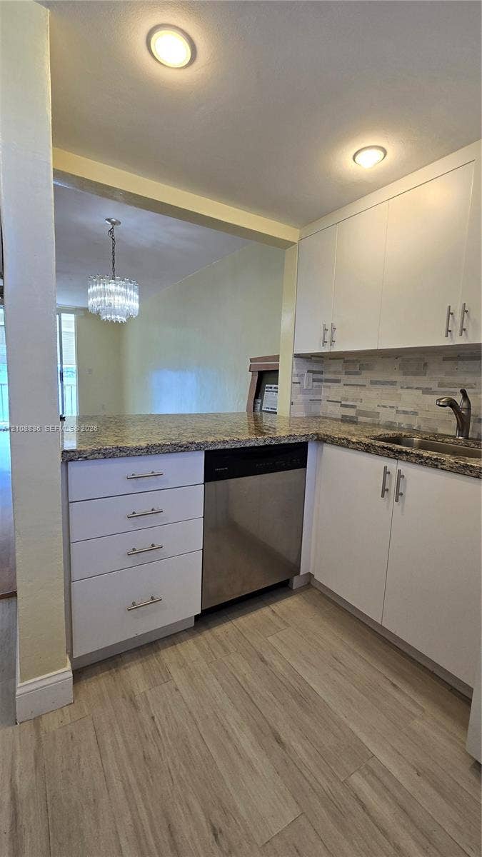 3000 Marcos Drive, #P304, Aventura, FL 33160 Kitchen featuring white cabinetry, stone-finish countertops, stainless steel dishwasher, decorative tile backsplash, and wood-finish flooring