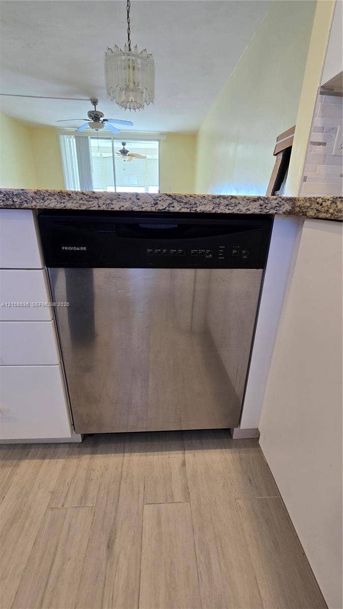 3000 Marcos Drive, #P304, Aventura, FL 33160 Stainless steel dishwasher, stone-finish countertop, white cabinetry, and wood-finish flooring